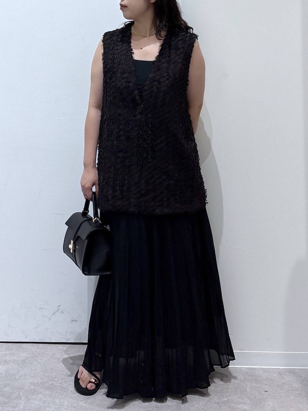 ブラック系のサンダル、ブラック系のスカート、ブラウン系のベストを着用したレディースの夏コーディネートの1枚目の写真