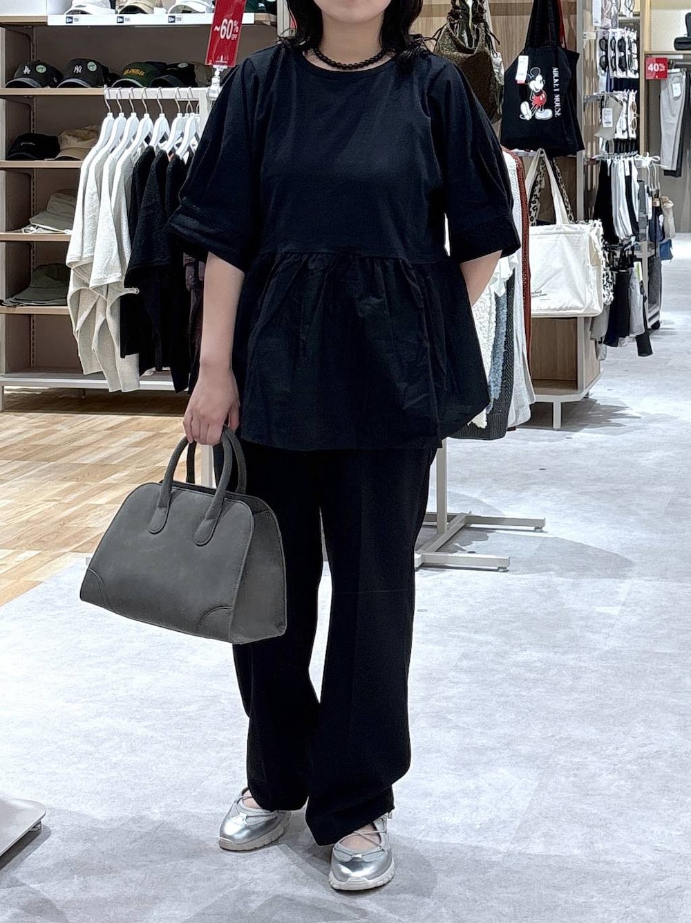 グレー系のスニーカー、ブラック系のスラックス、グリーン系のショルダーバッグを着用したレディースの秋コーディネートの1枚目の写真