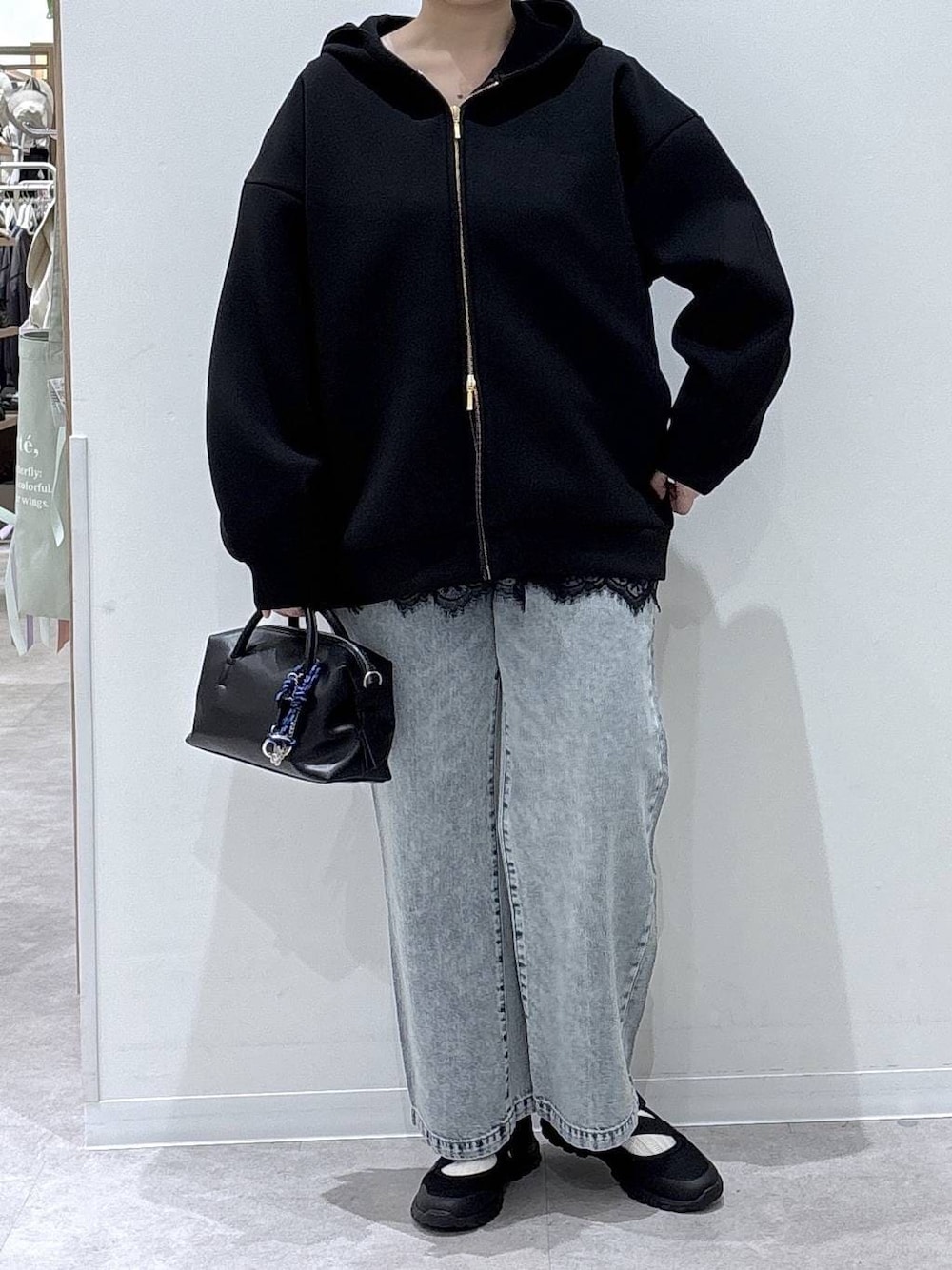 ブラック系のスニーカー、ブルー系のデニムパンツ、ブラック系のパーカーを着用したレディースの春コーディネートの1枚目の写真