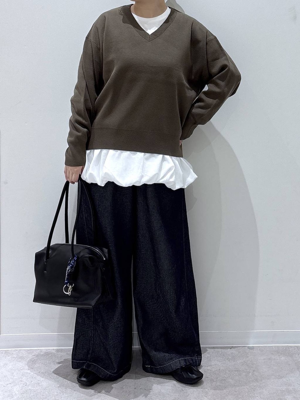 ブラック系のボストンバッグ、ホワイト系のTシャツ/カットソー、ブラウン系のニット/セーターを着用したレディースの秋コーディネートの1枚目の写真