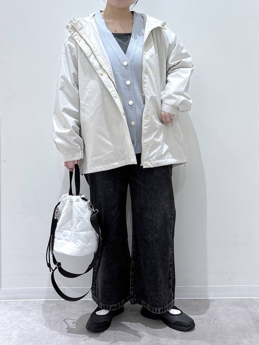 ブラック系のデニムパンツ、ホワイト系のハンドバッグ、ベージュ系のパーカーを着用したレディースの春コーディネートの1枚目の写真