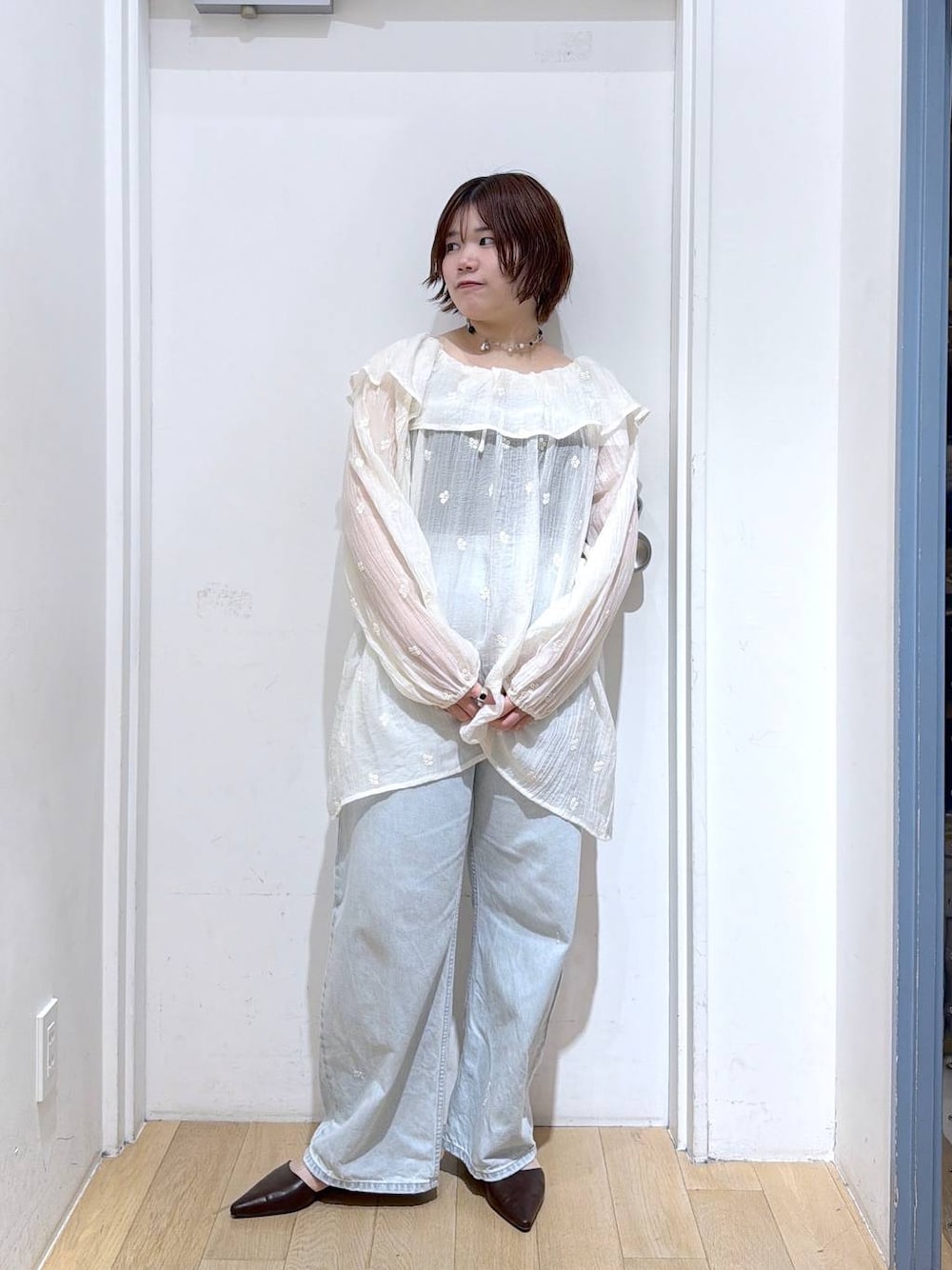 ブルー系のデニムパンツ、ブラウン系のサンダル、ホワイト系のワンピースを着用したレディースの春コーディネートの1枚目の写真