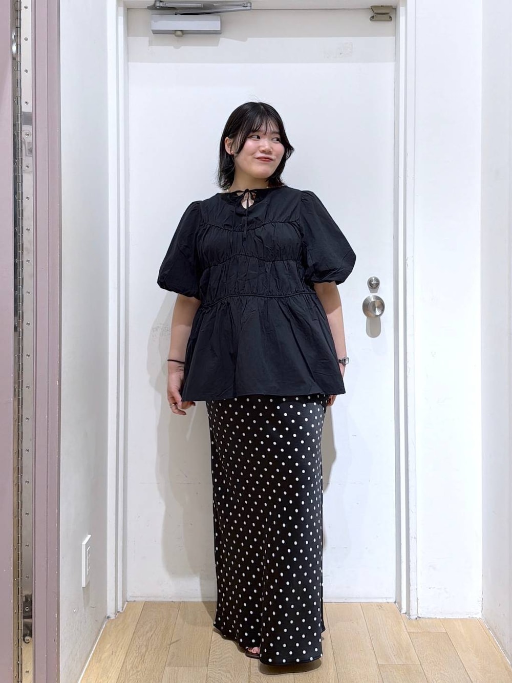 ブラック系のシャツ/ブラウス、ブラック系のスカート、ブラウン系のサンダルを着用したレディースの夏コーディネートの1枚目の写真