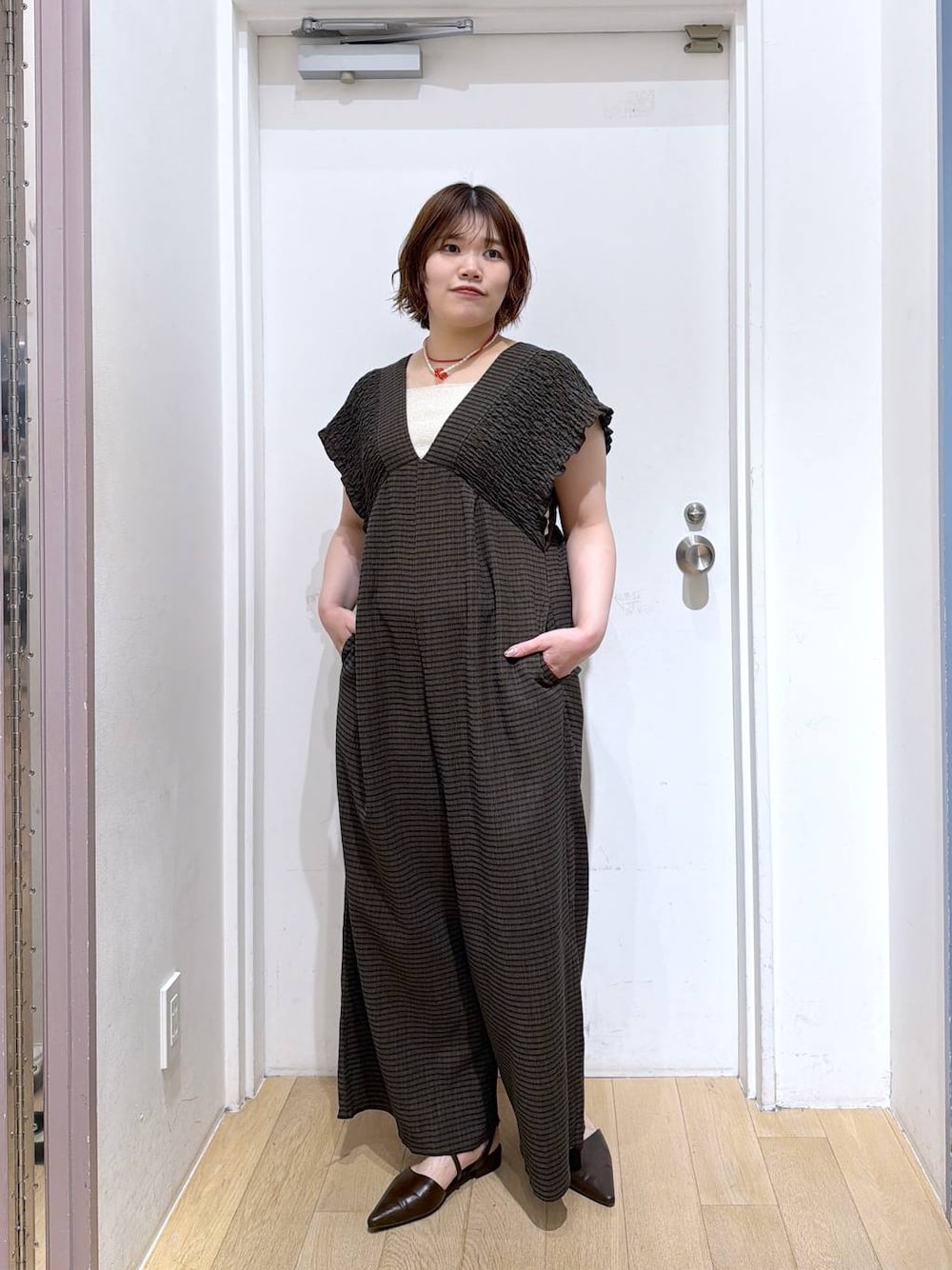 ブラウン系のサロペット/オーバーオール、ゴールド系のタンクトップ、ブラウン系のサンダルを着用したレディースの春コーディネートの1枚目の写真