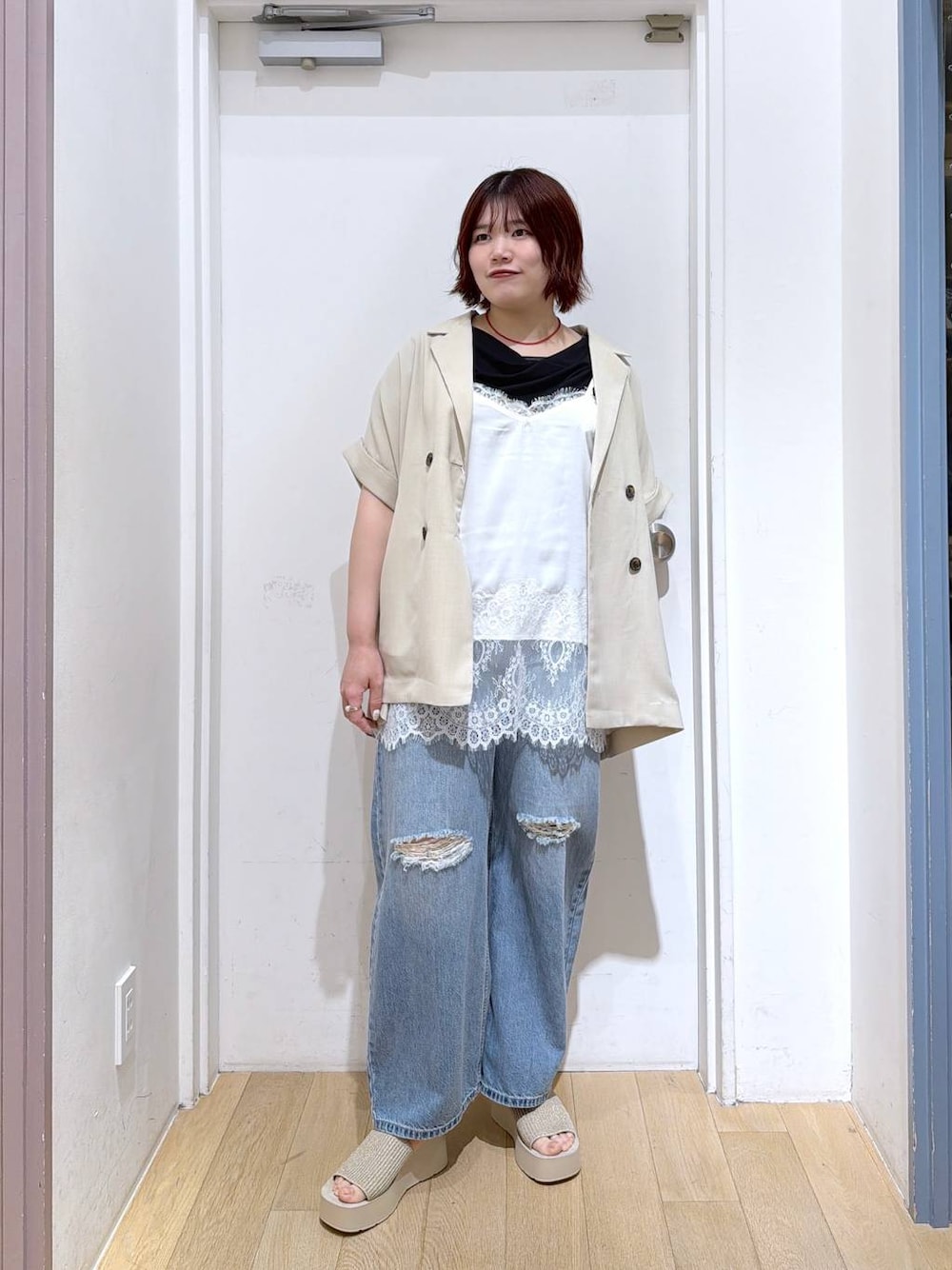 ブルー系のデニムパンツ、ホワイト系のテーラードジャケット、ホワイト系のサンダルを着用したレディースの春コーディネートの1枚目の写真