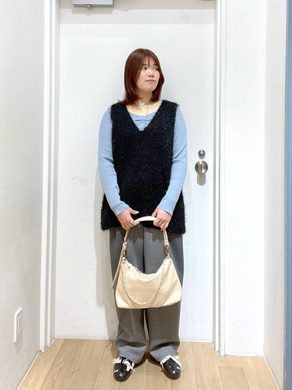 グレー系のスウェットパンツ、ベージュ系のショルダーバッグ、ブルー系のニット/セーターを着用したレディースの冬コーディネートの1枚目の写真