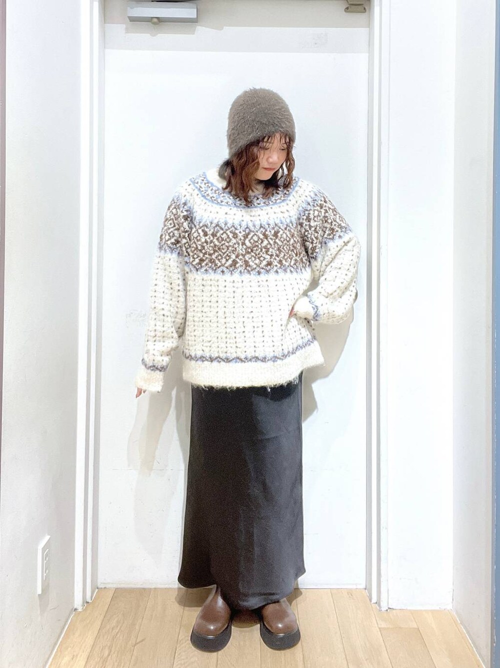 ブラック系のスカート、ブラウン系のサンダル、ホワイト系のニット/セーターを着用したレディースの冬コーディネートの1枚目の写真