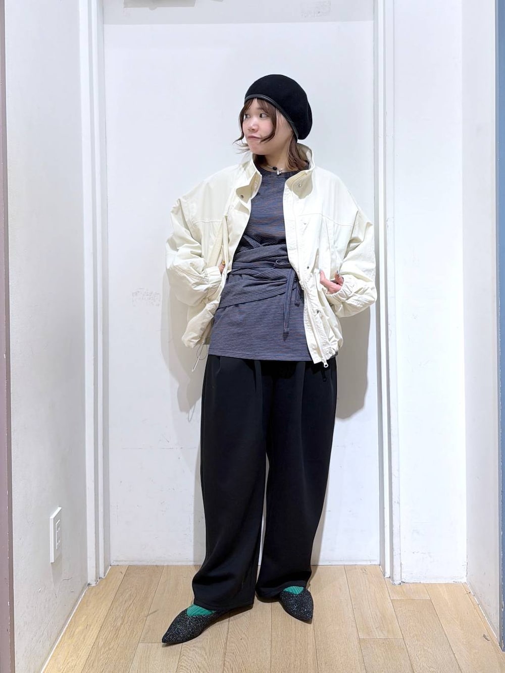 ホワイト系のナイロンジャケット、ブラック系のスウェットパンツ、ブラック系のパンプスを着用したレディースの冬コーディネートの1枚目の写真