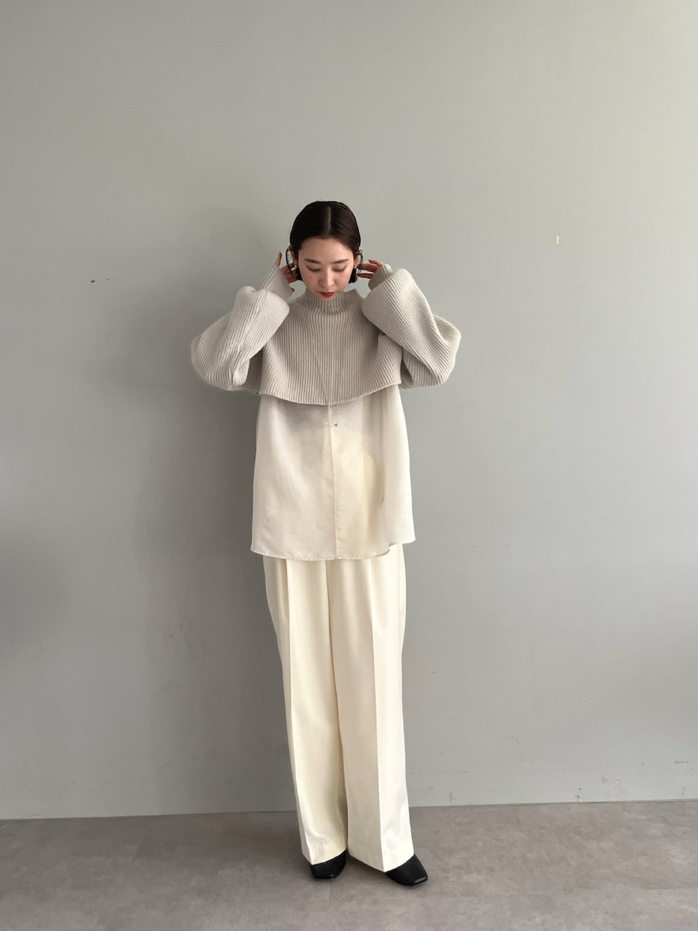 ベージュ系のニット/セーター、ホワイト系のスラックス、ブラック系のブーツを着用したレディースの秋コーディネートの1枚目の写真