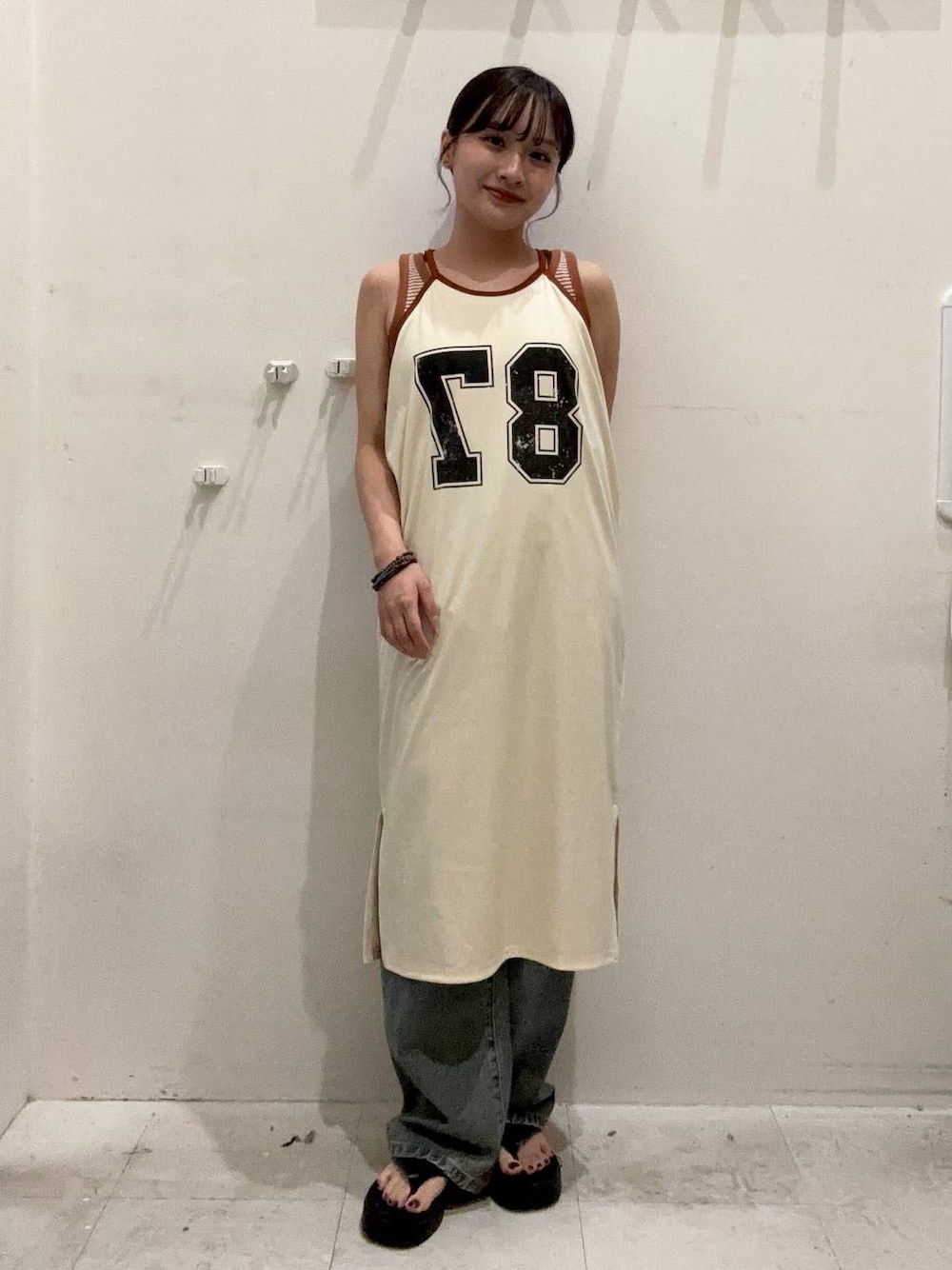 ブルー系のデニムパンツ、ベージュ系のタンクトップ、ブラック系のサンダルを着用したレディースの夏コーディネートの1枚目の写真