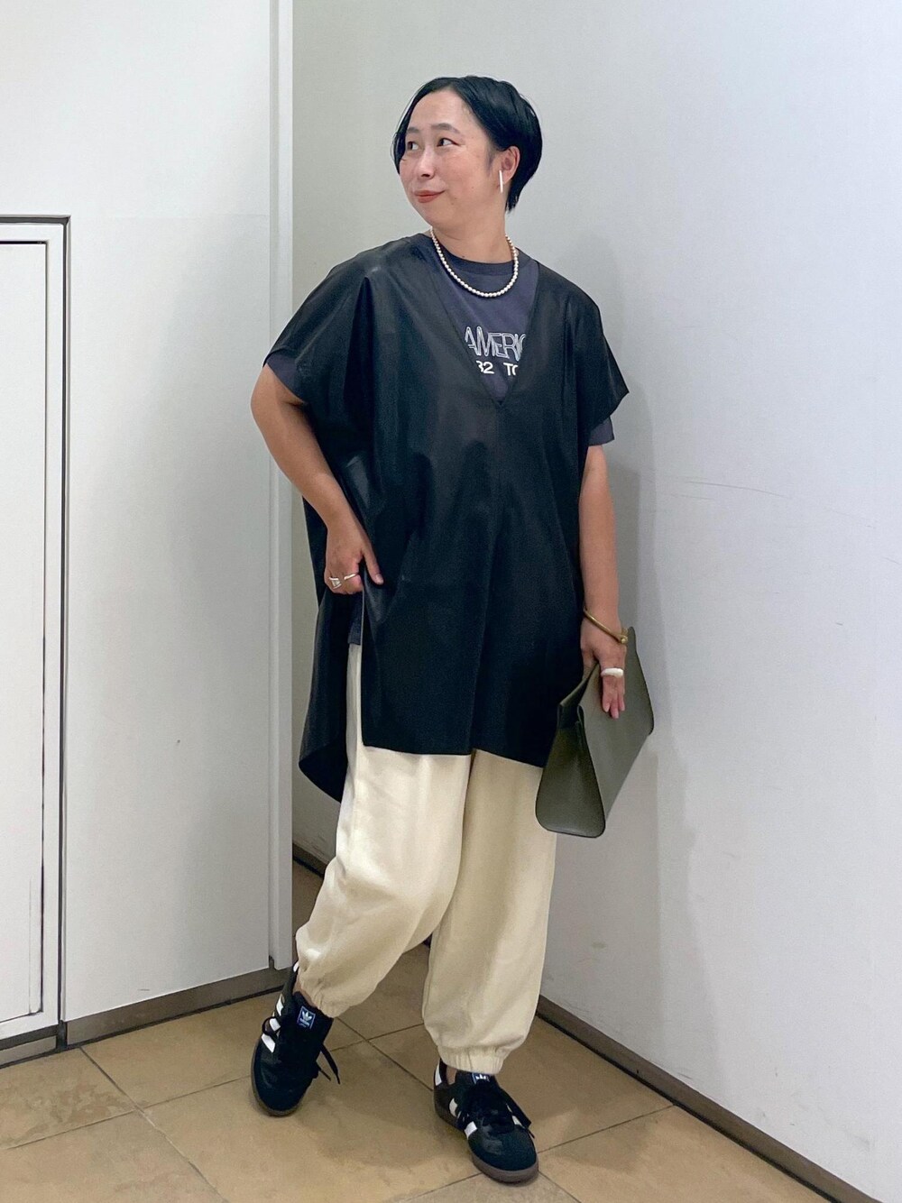 グリーン系のショルダーバッグ、ブラック系のTシャツ/カットソー、ホワイト系のスウェットパンツを着用したレディースの夏コーディネートの1枚目の写真