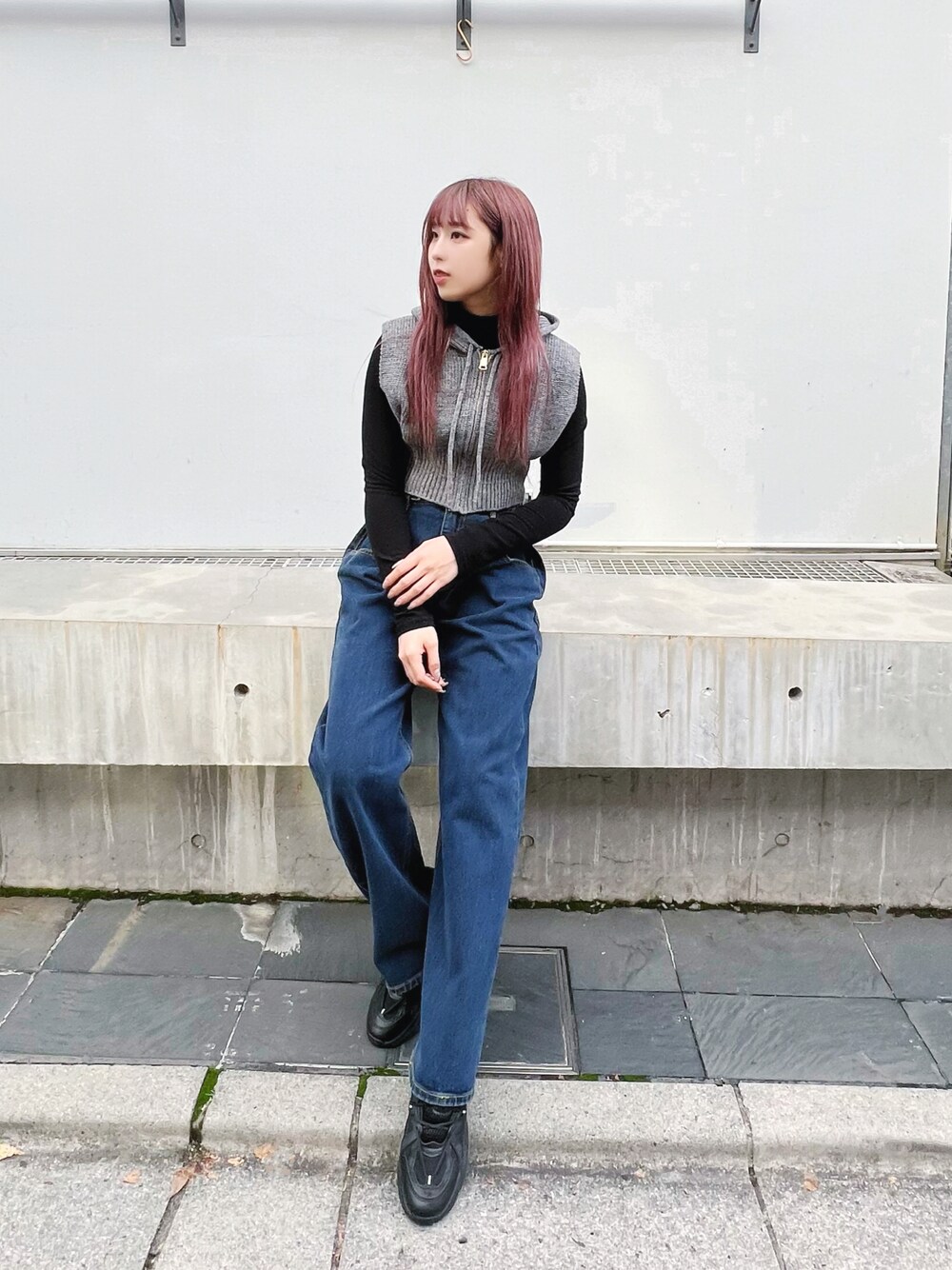ブルー系のデニムパンツ、ブラック系のスニーカー、グレー系のベストを着用したレディースの冬コーディネートの1枚目の写真