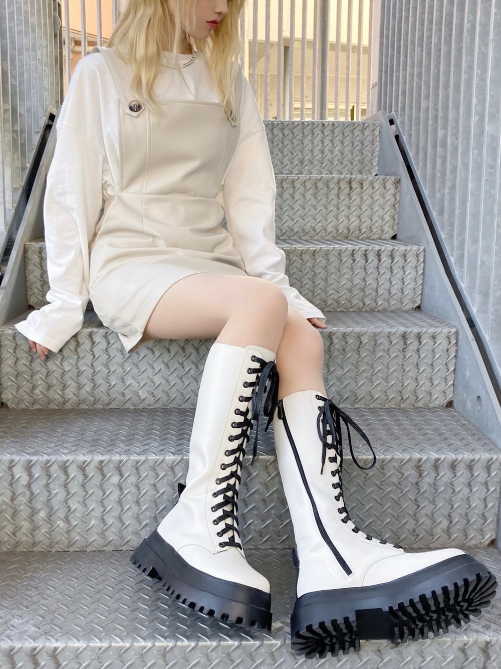 ホワイト系のジャンパースカート、ホワイト系のブーツ、ホワイト系のTシャツ/カットソーを着用したレディースの秋コーディネートの1枚目の写真