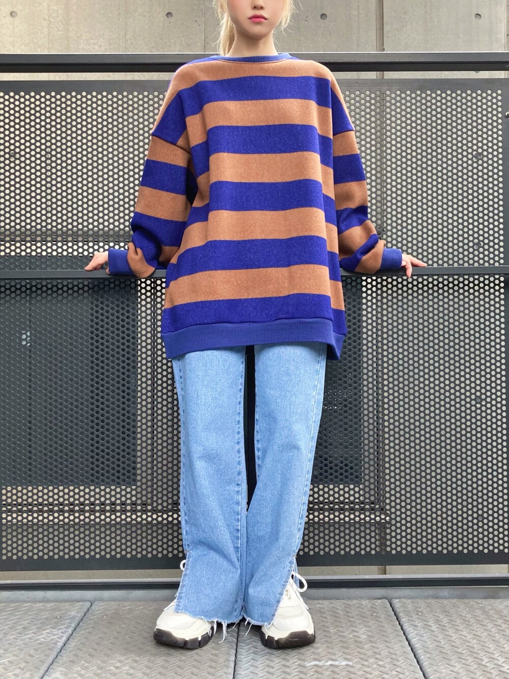 ブルー系のニット/セーター、ブルー系のデニムパンツ、ホワイト系のスニーカーを着用したレディースの秋コーディネートの1枚目の写真