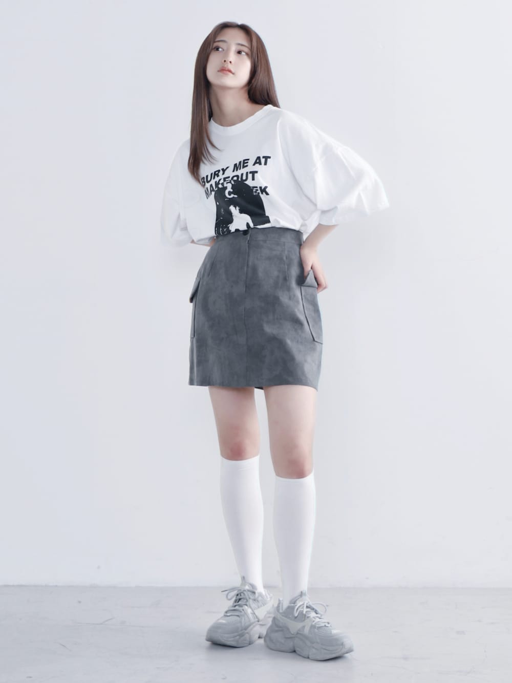 ホワイト系のTシャツ/カットソー、ブラック系のスカート、グレー系のスニーカーを着用したレディースの夏コーディネートの1枚目の写真