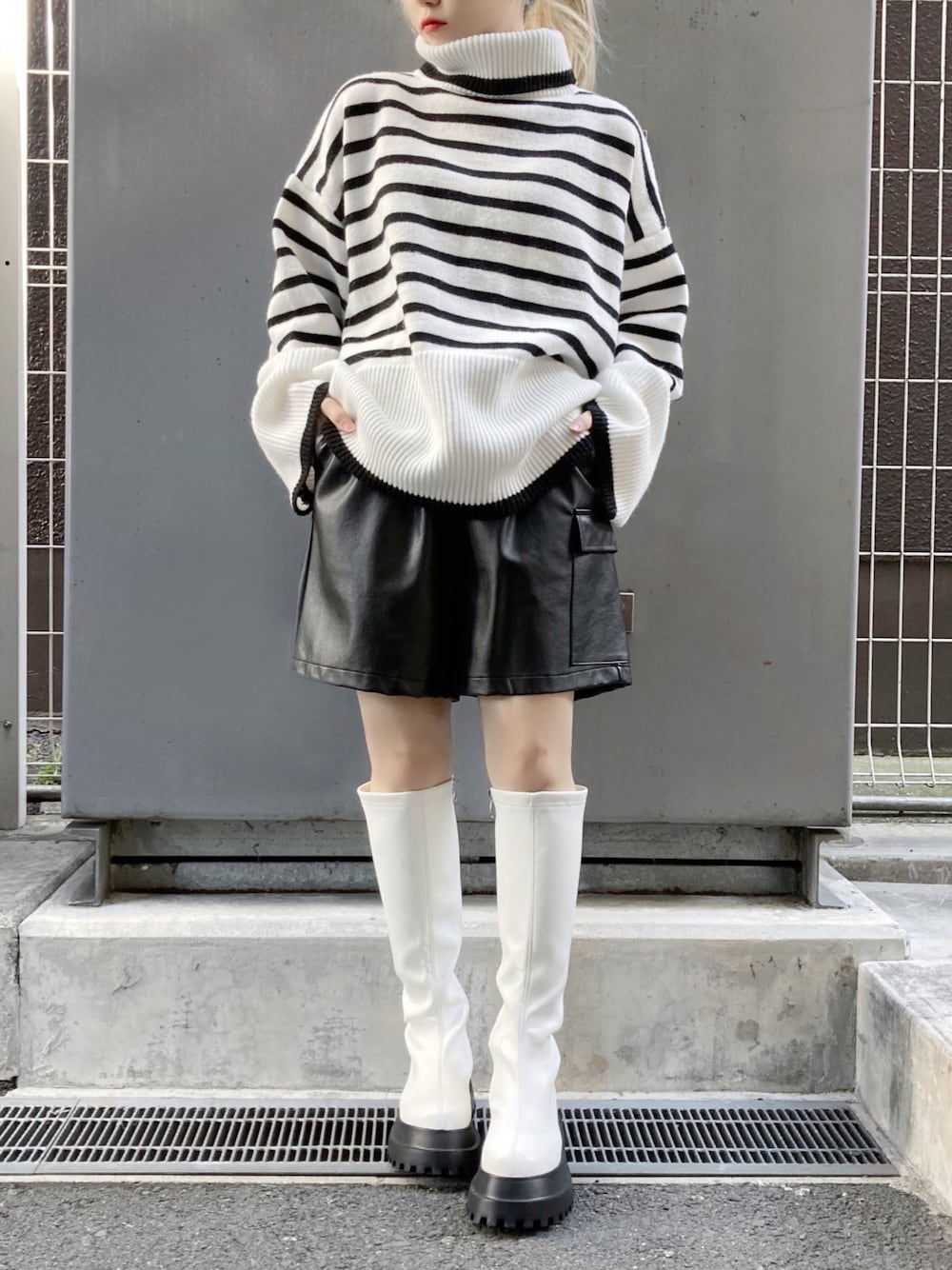 ホワイト系のブーツ、ブラック系のその他パンツ、ホワイト系のニット/セーターを着用したレディースの冬コーディネートの1枚目の写真