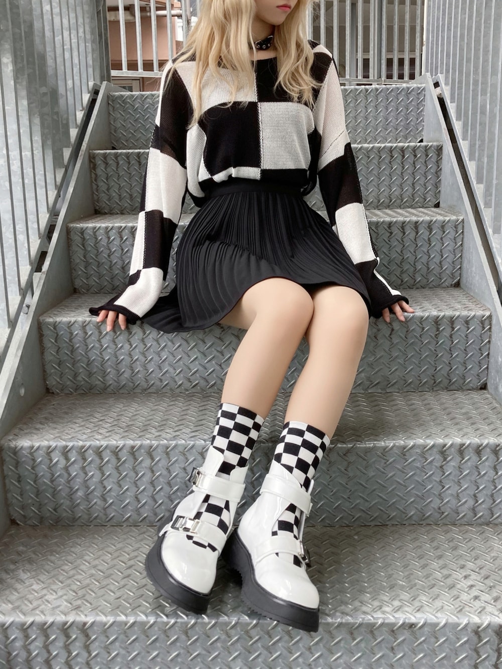 ブラック系のニット/セーター、ブラック系のスカート、ホワイト系のブーツを着用したレディースの秋コーディネートの1枚目の写真