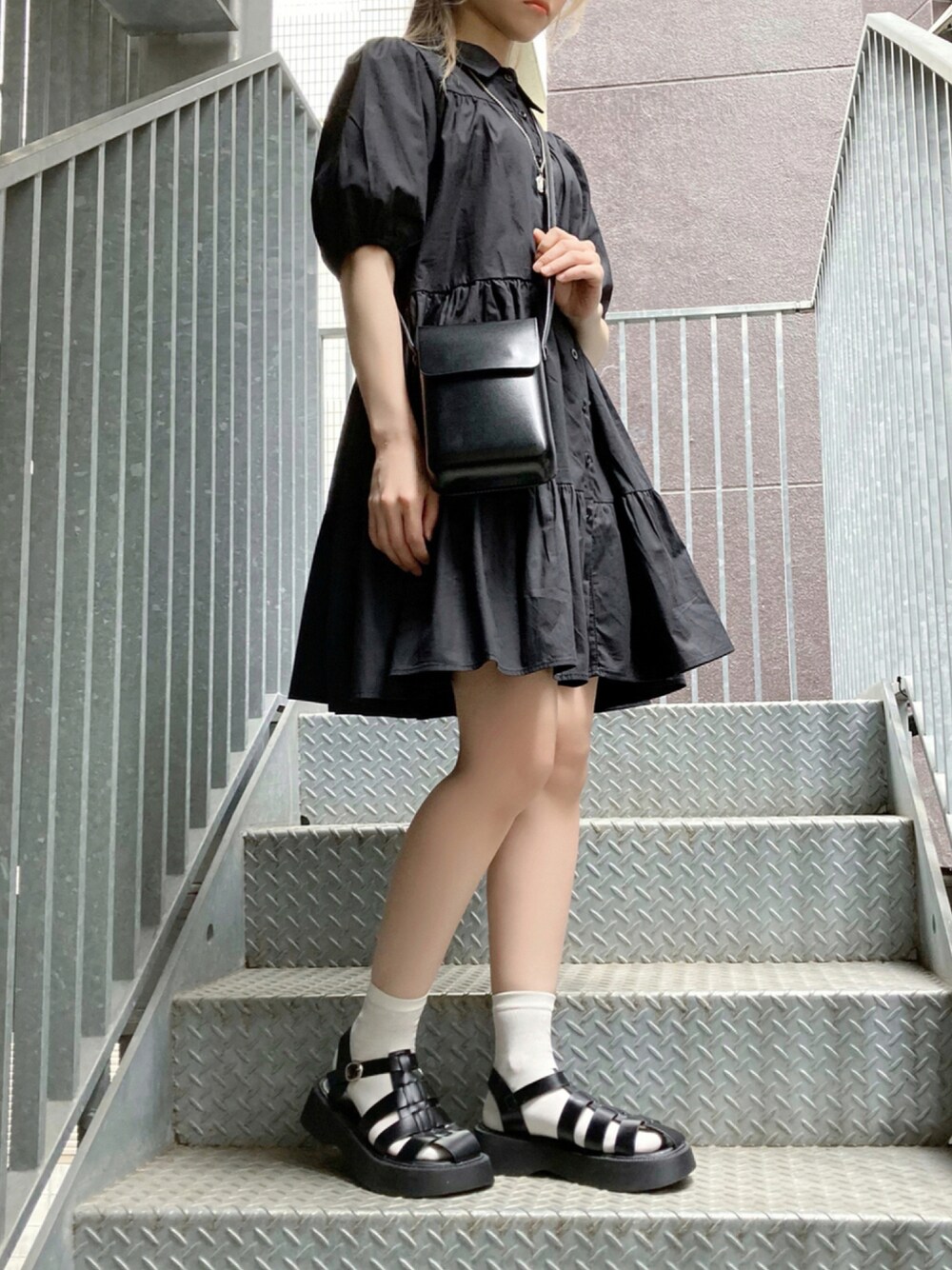 ブラック系のショルダーバッグ、ブラック系のワンピース、ブラック系のサンダルを着用したレディースの夏コーディネートの1枚目の写真