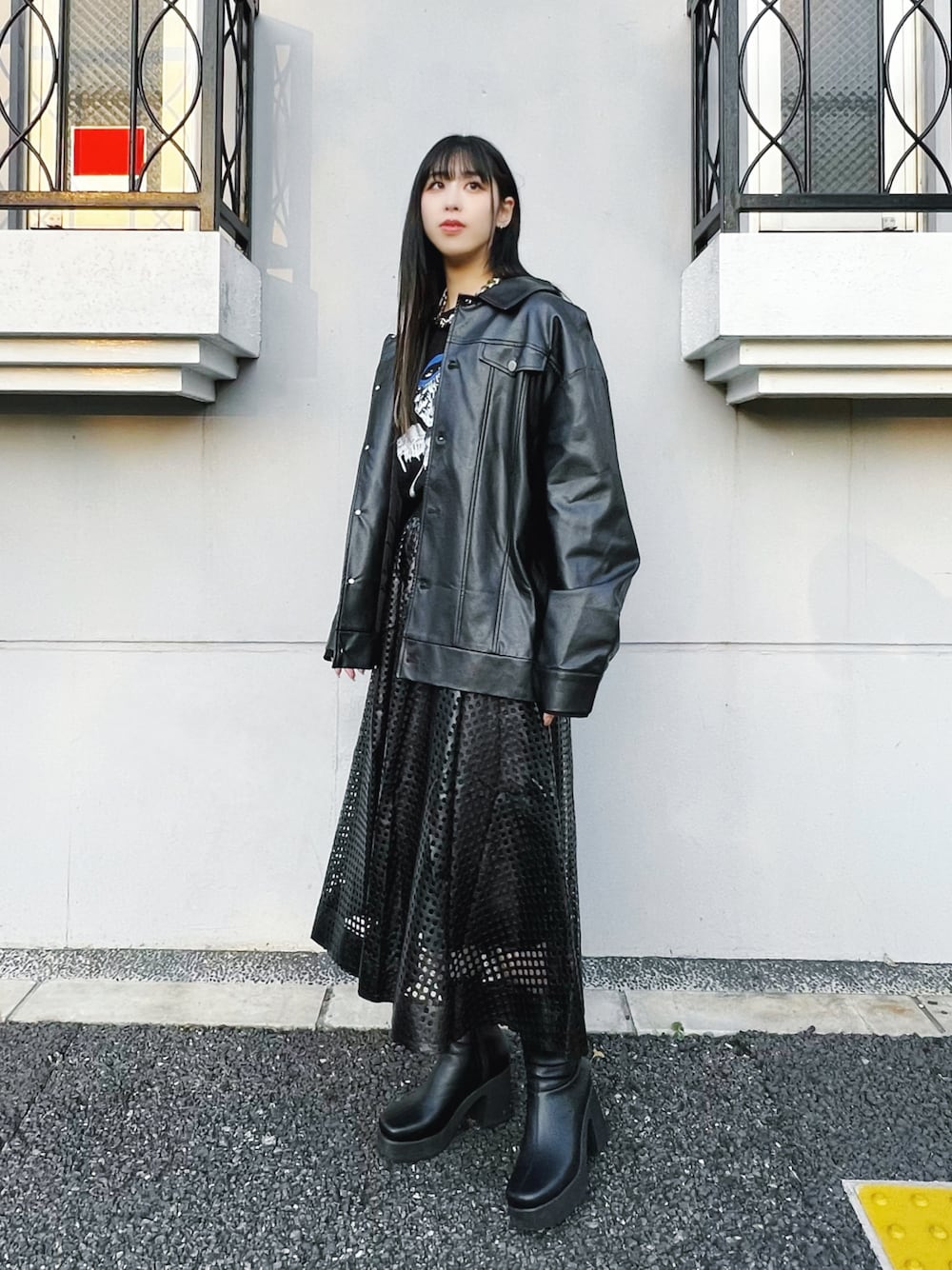 ブラック系のライダースジャケット、ブラック系のスカート、ブラック系のブーツを着用したレディースの冬コーディネートの1枚目の写真