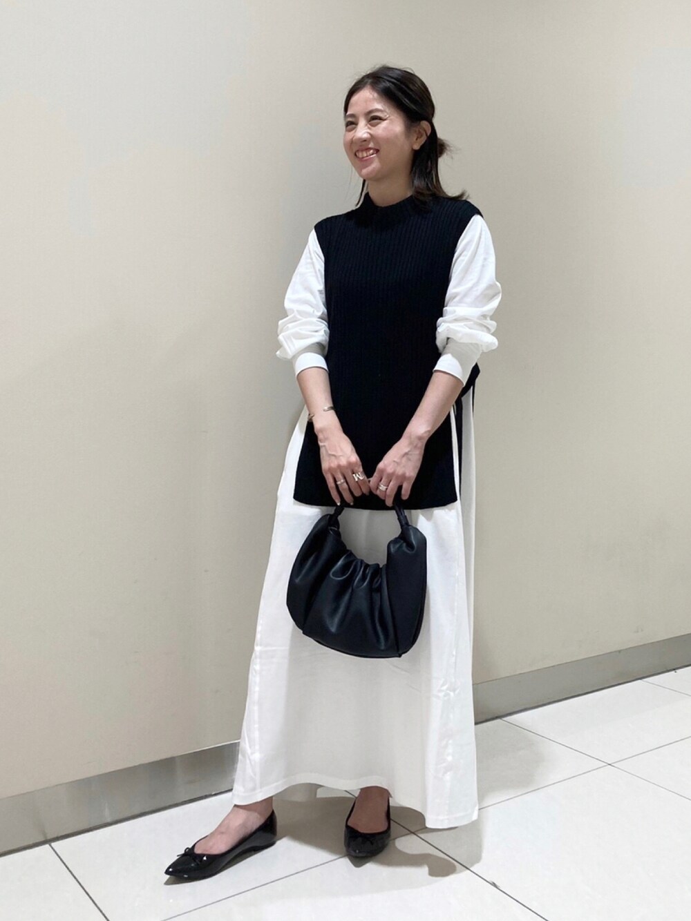 ホワイト系のワンピース、ブラック系のバッグを着用したレディースの秋コーディネートの1枚目の写真