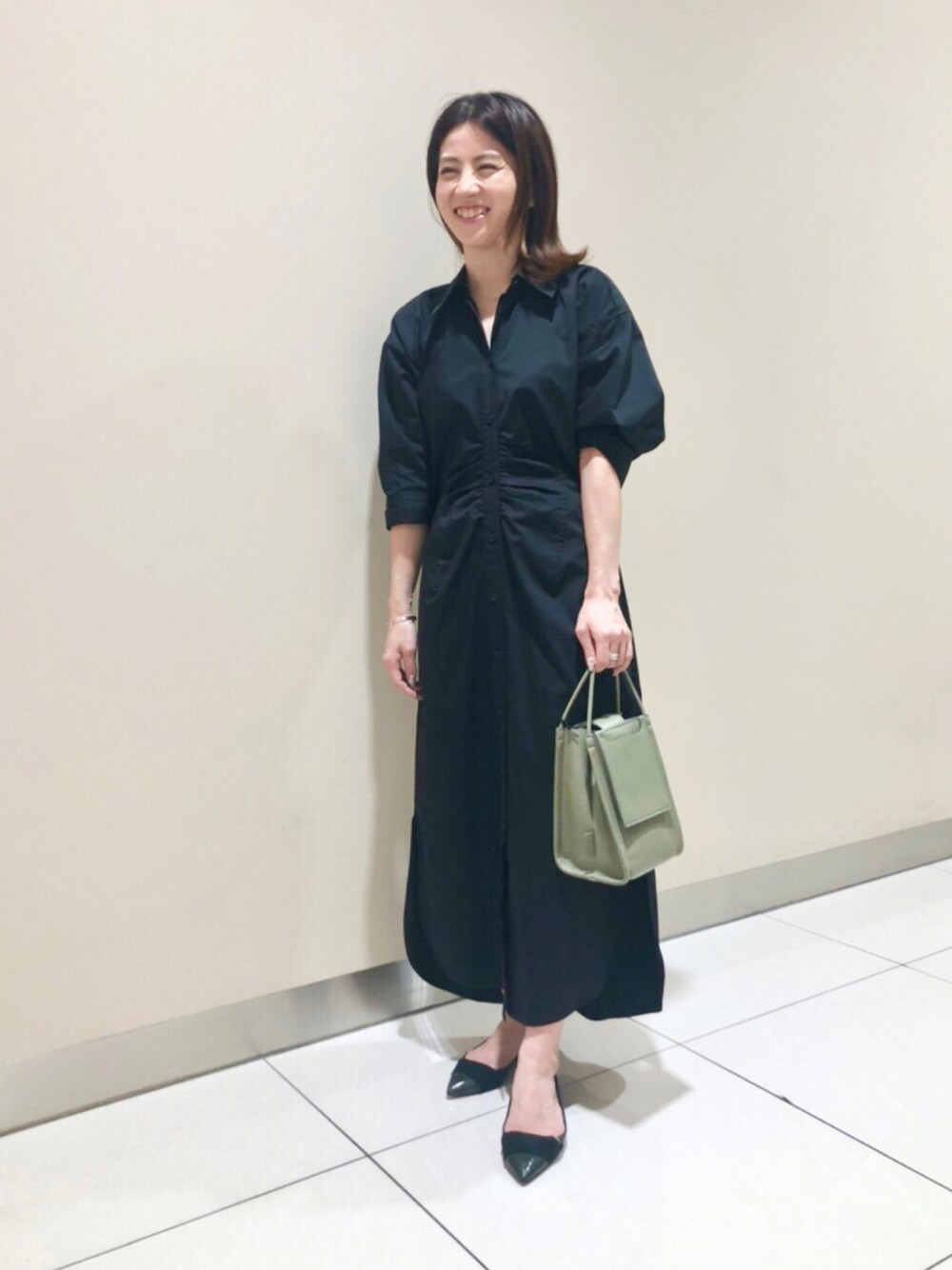 ブラック系のワンピース、グリーン系のショルダーバッグを着用したレディースの秋コーディネートの1枚目の写真