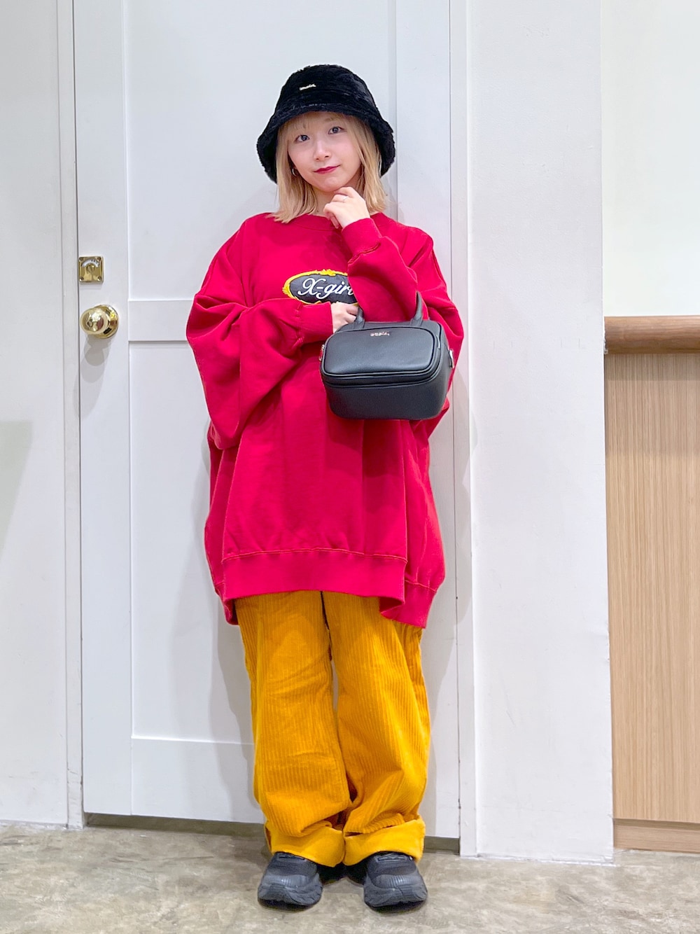 レッド系のスウェット、ブラック系のショルダーバッグ、イエロー系のその他パンツを着用したレディースの秋コーディネートの1枚目の写真