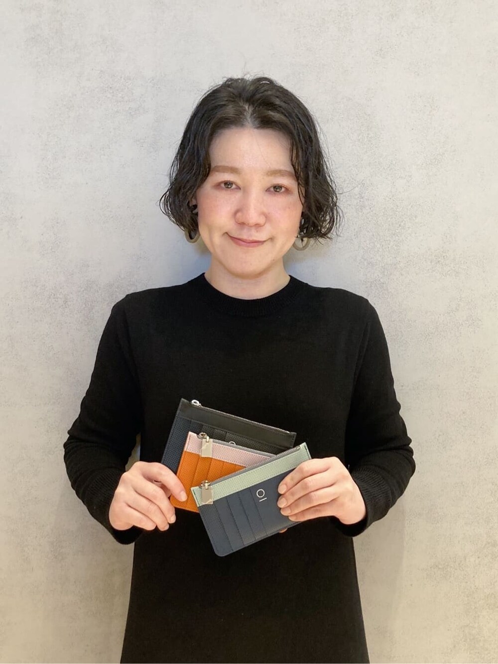 オレンジ系の財布、ブラック系の財布、ブルー系の財布を着用したレディースの冬コーディネートの1枚目の写真