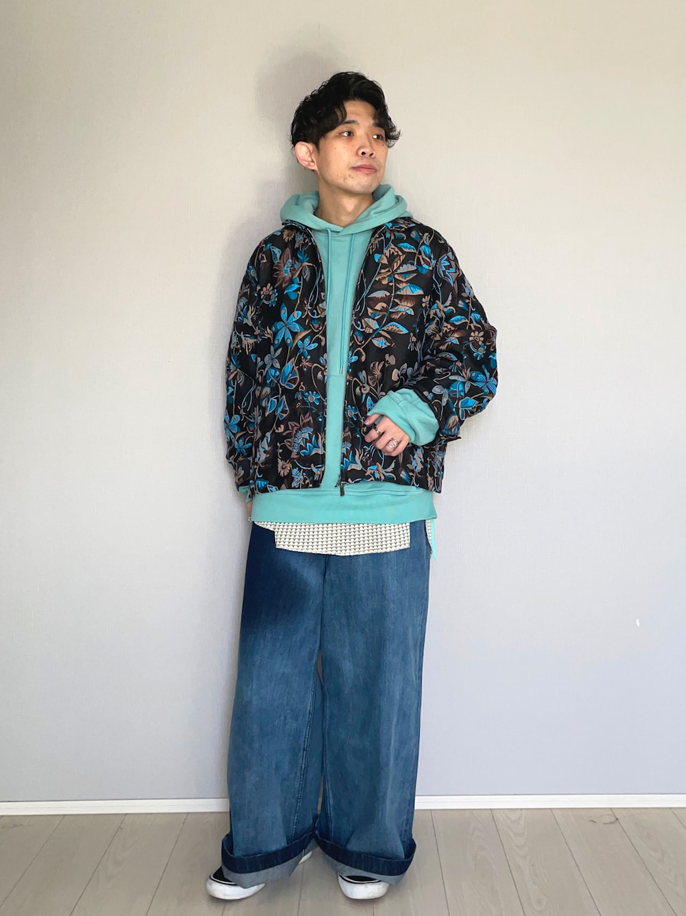 ブラック系のスニーカー、ブルー系のデニムパンツ、グリーン系のパーカーを着用したメンズの春コーディネートの1枚目の写真