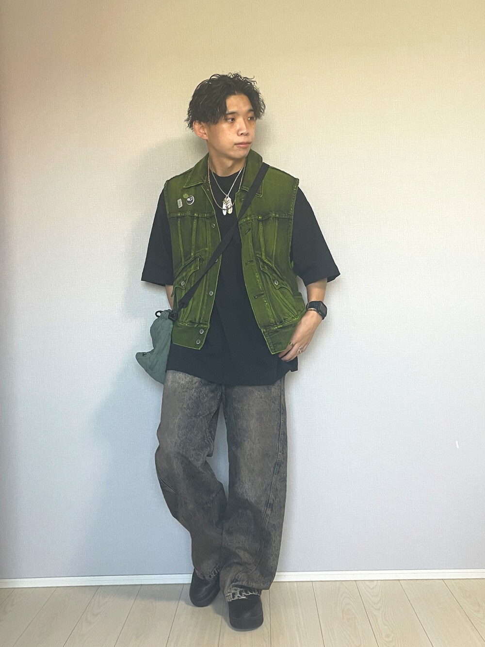 ブラック系のスニーカー、ブルー系のデニムパンツ、イエロー系のベストを着用したメンズの秋コーディネートの1枚目の写真