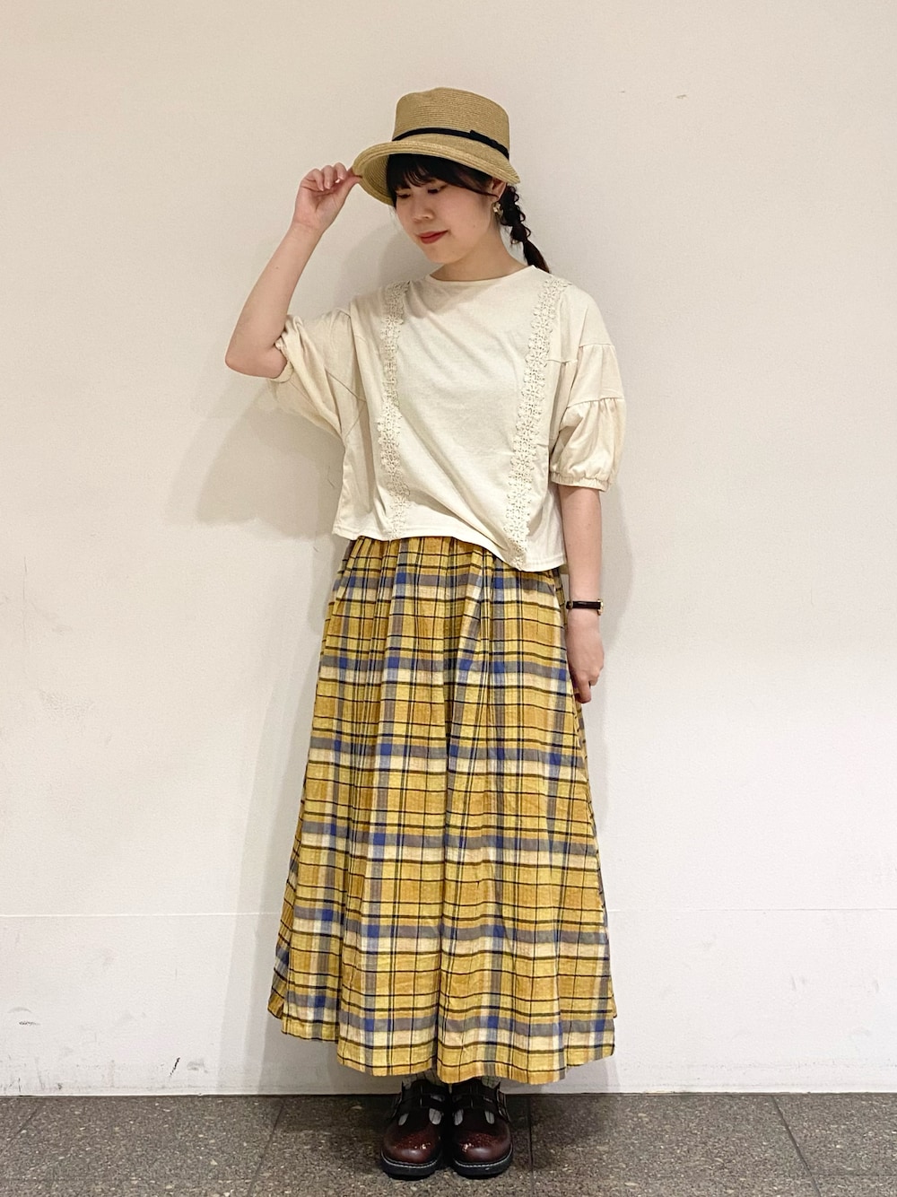 イエロー系のスカート、ホワイト系のTシャツ/カットソー、ベージュ系のハットを着用したレディースの夏コーディネートの1枚目の写真