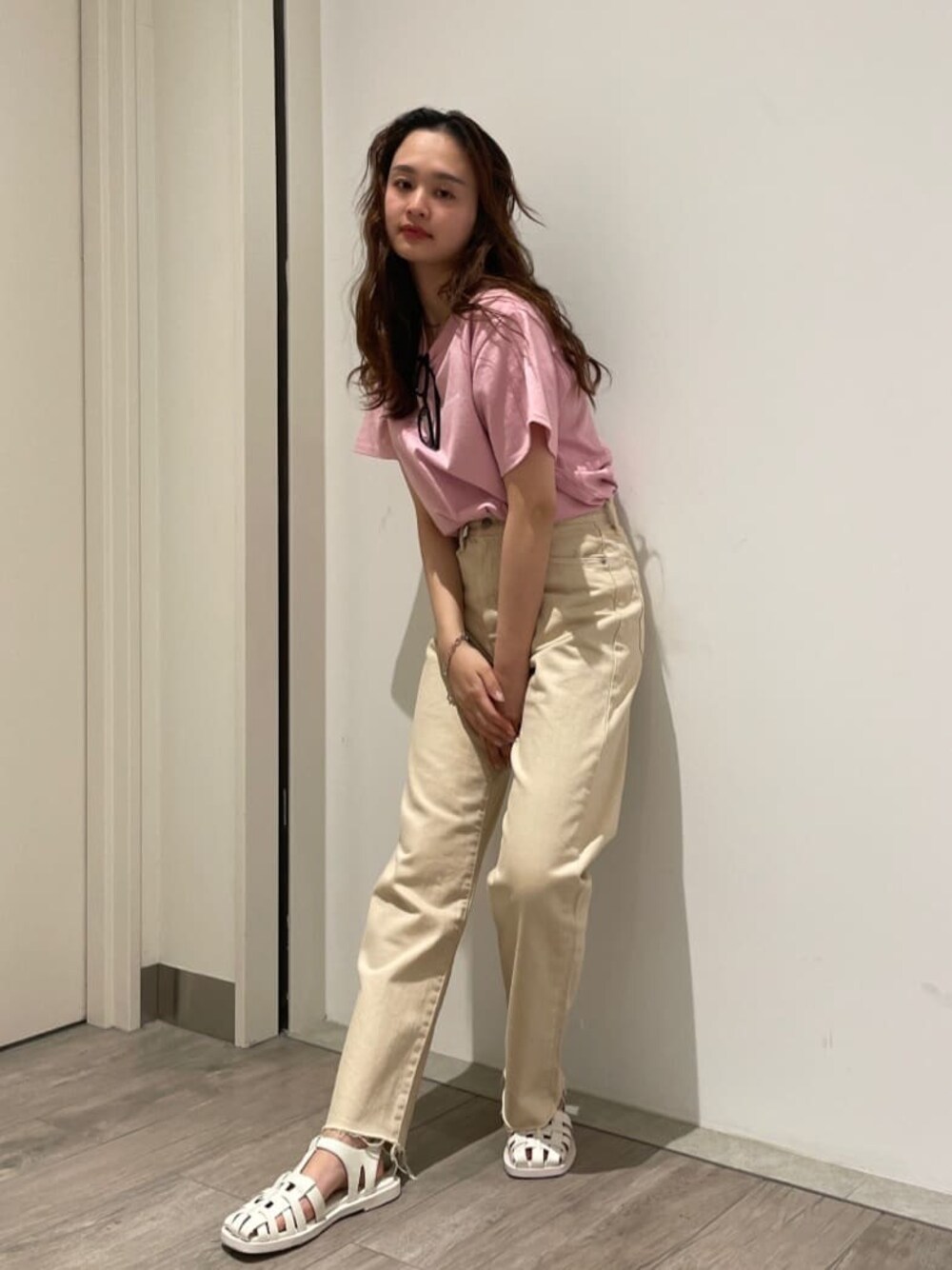 ホワイト系のデニムパンツ、ホワイト系のサンダル、ピンク系のTシャツ/カットソーを着用したレディースの春コーディネートの1枚目の写真