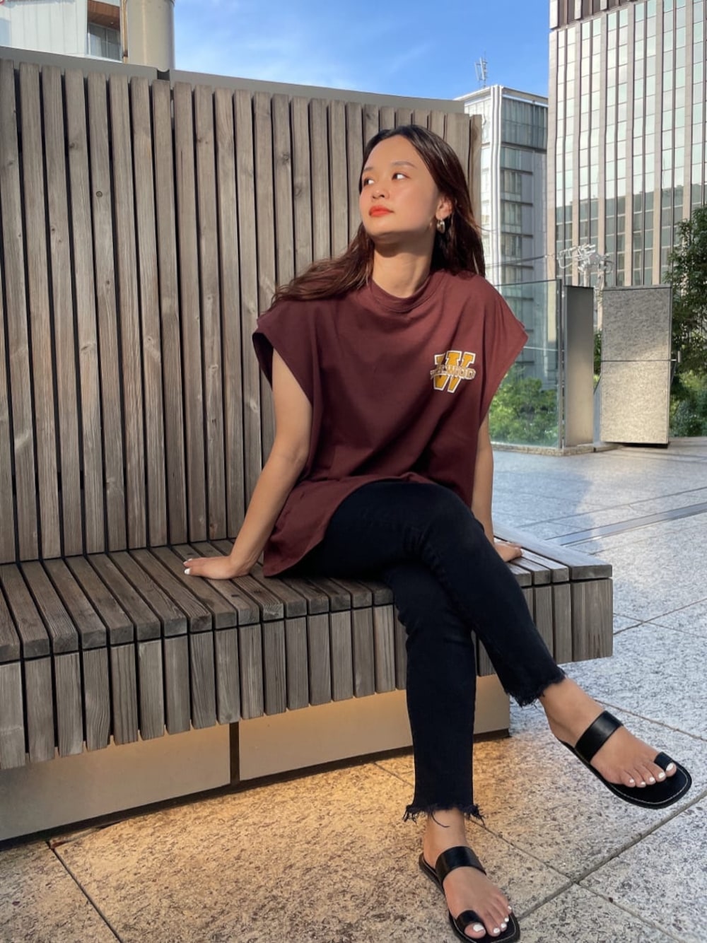 ブラック系のデニムパンツ、ブラック系のサンダル、ブラウン系のTシャツ/カットソーを着用したレディースの夏コーディネートの1枚目の写真