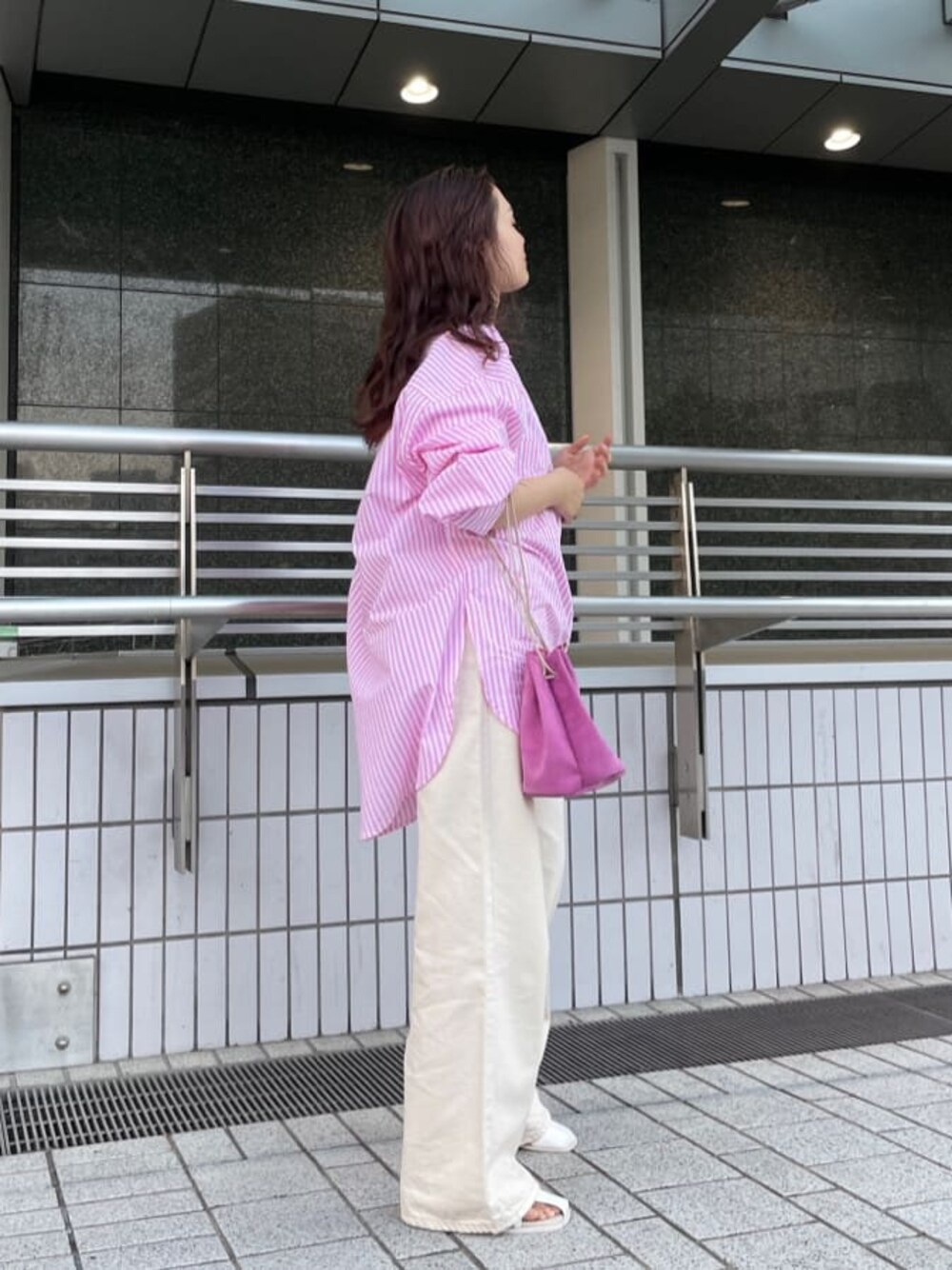 ピンク系のハンドバッグ、ピンク系のシャツ/ブラウス、ホワイト系のサンダルを着用したレディースの春コーディネートの1枚目の写真