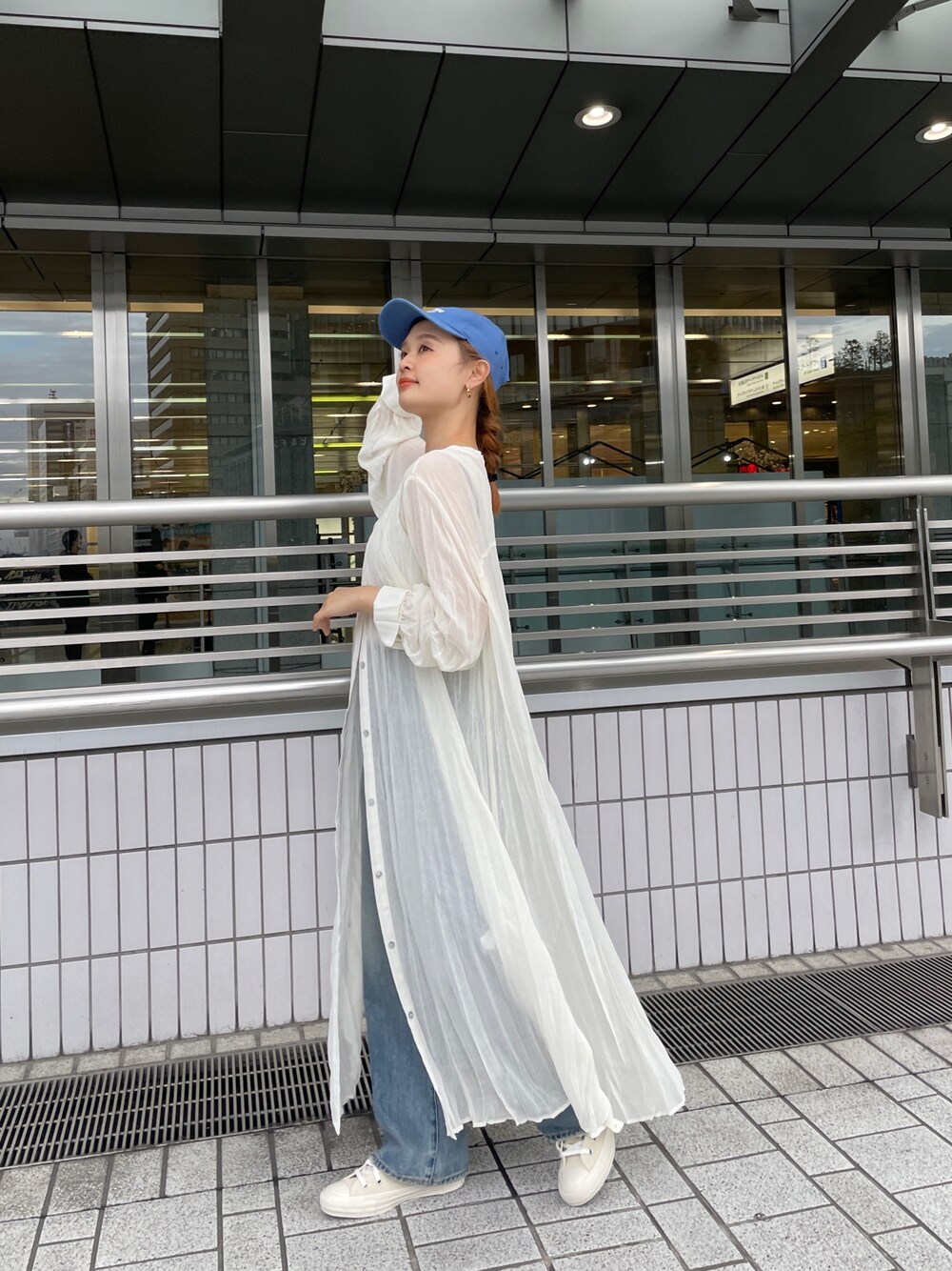 ブルー系のデニムパンツ、ホワイト系のスニーカー、ホワイト系のタンクトップを着用したレディースの春コーディネートの1枚目の写真