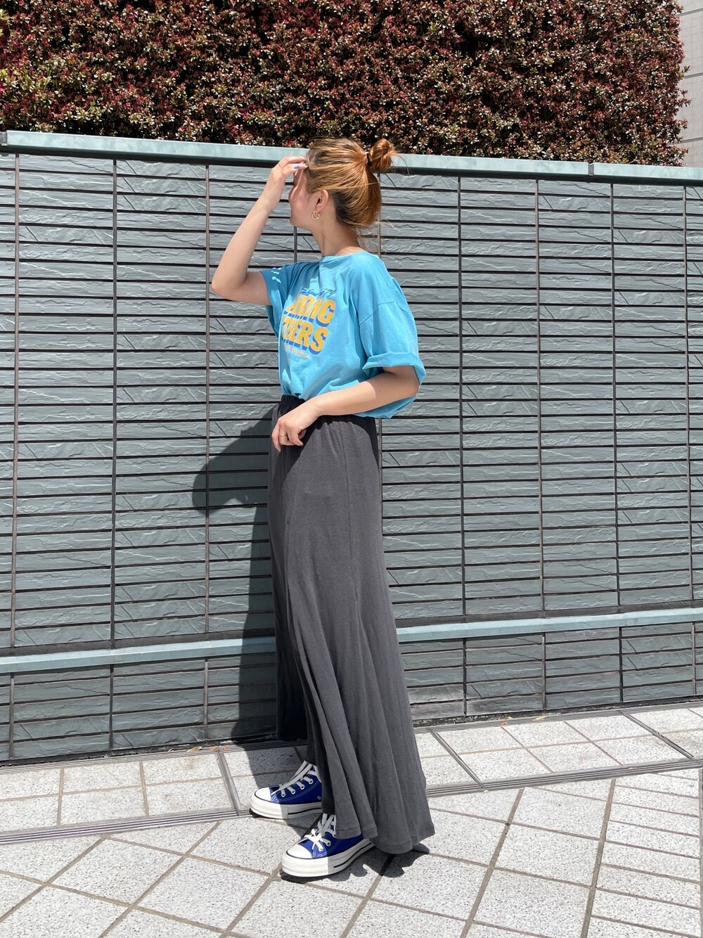 ブルー系のTシャツ/カットソー、グレー系のスカート、ブルー系のスニーカーを着用したレディースの春コーディネートの1枚目の写真