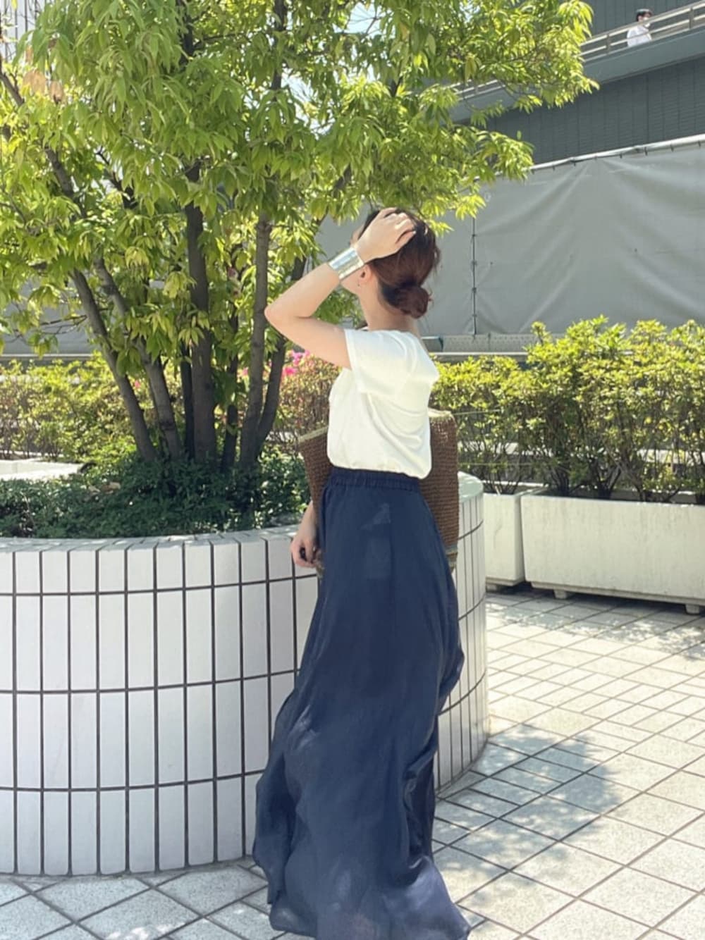 ブラウン系のトートバッグ、ホワイト系のTシャツ/カットソー、ブルー系のスカートを着用したレディースの春コーディネートの1枚目の写真