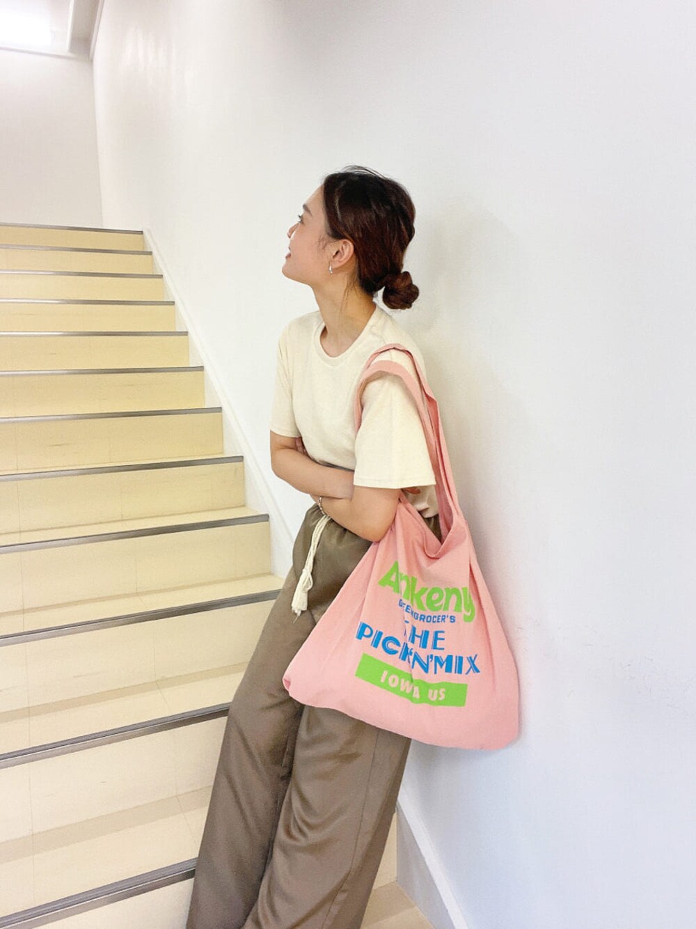 ピンク系のエコバッグ/サブバッグ、ブラウン系のその他パンツ、ホワイト系のTシャツ/カットソーを着用したレディースの夏コーディネートの1枚目の写真