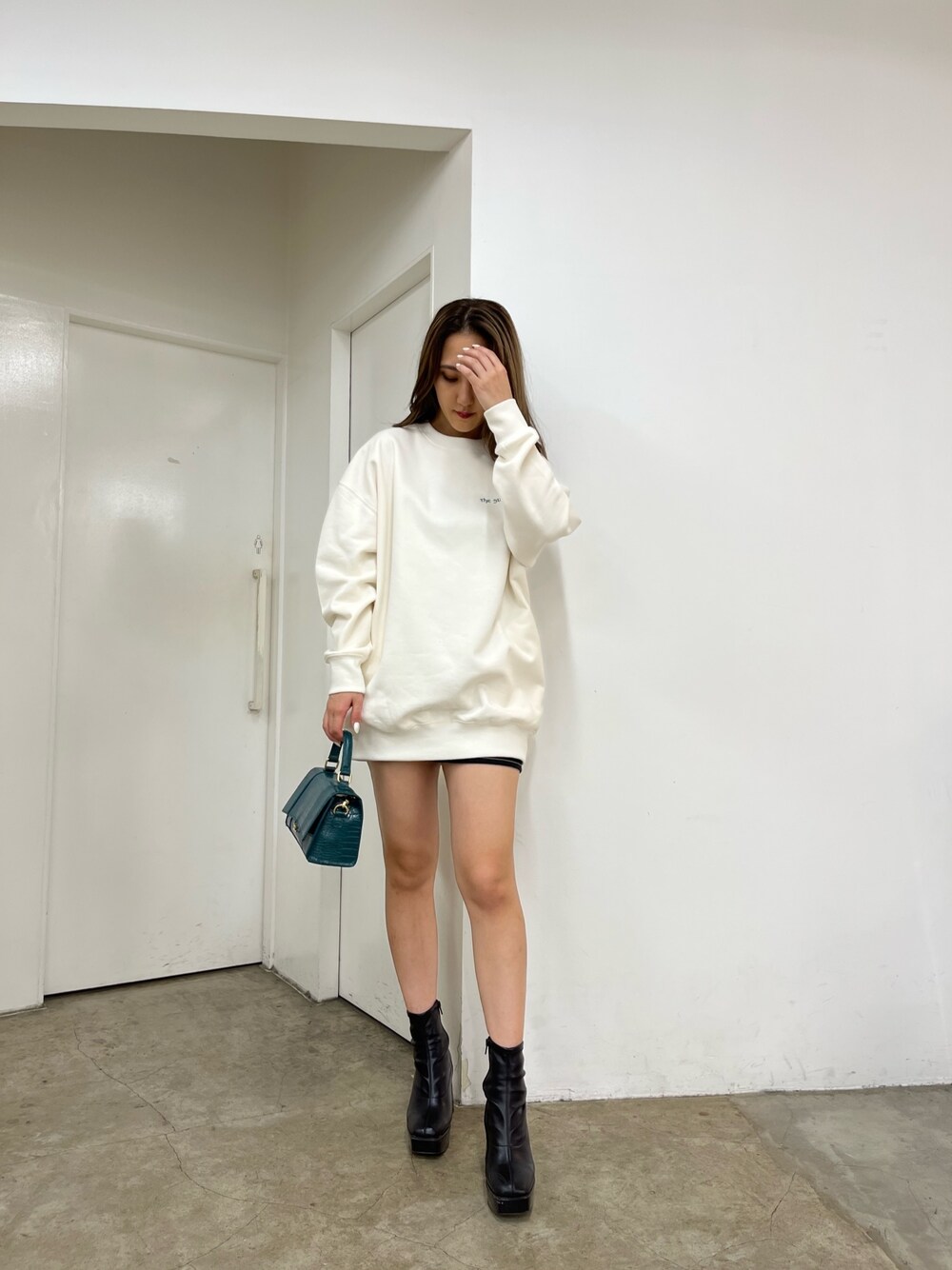 ホワイト系のスウェット、ブラック系のデニムスカート、ブラック系のブーツを着用したレディースの秋コーディネートの1枚目の写真