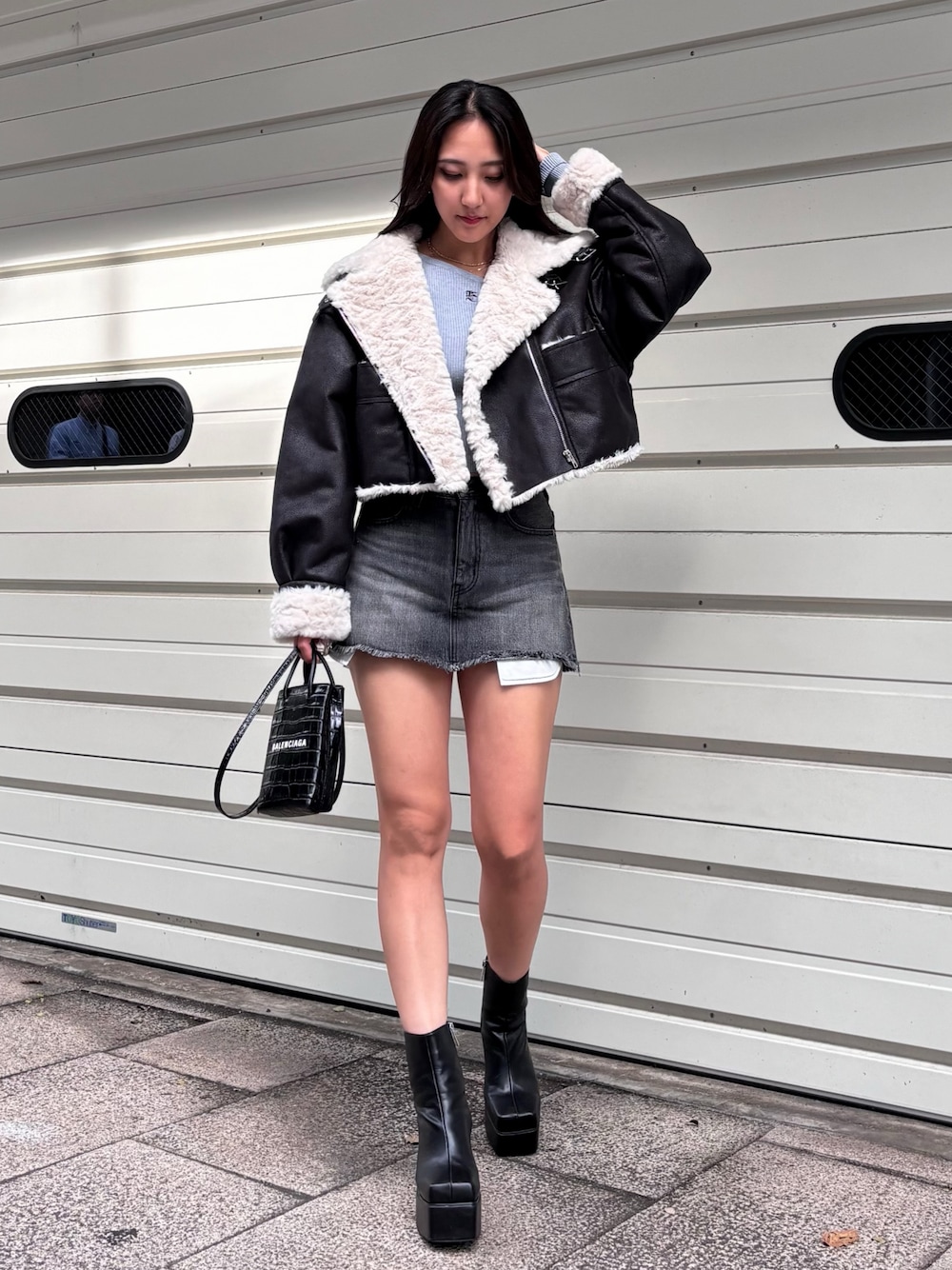 ブラック系のブルゾン、グレー系のニット/セーター、ブラック系のデニムスカートを着用したレディースの冬コーディネートの1枚目の写真