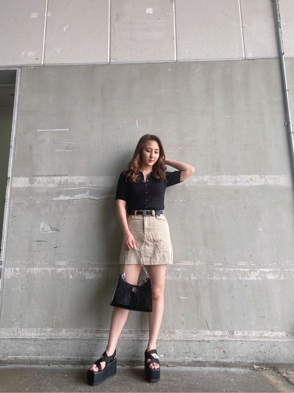 ベージュ系のデニムスカート、ブラック系のサンダル、ブラック系のTシャツ/カットソーを着用したレディースの夏コーディネートの1枚目の写真