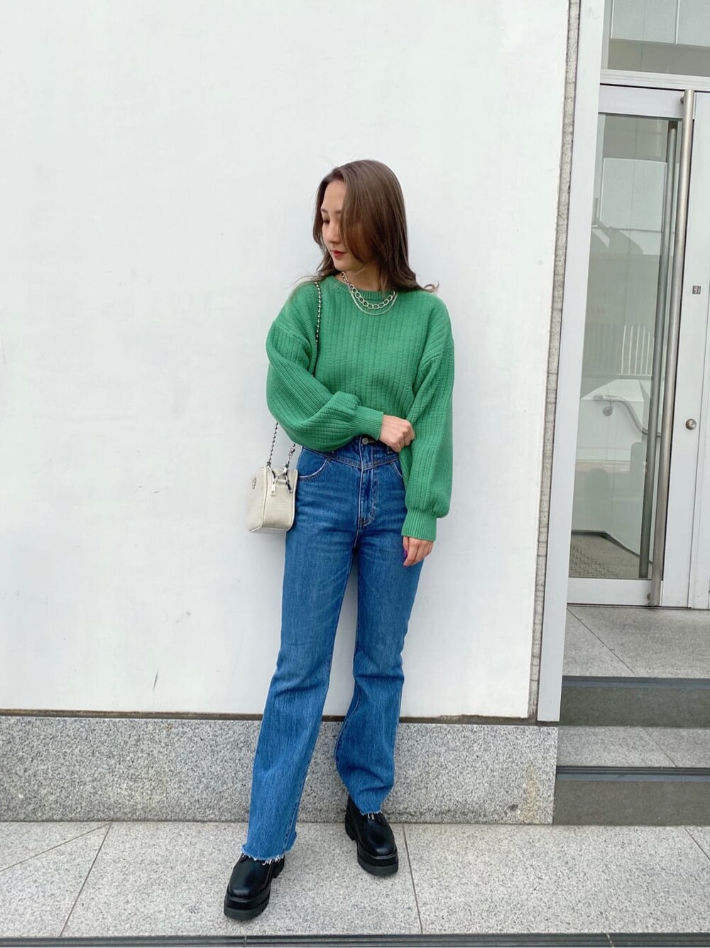 ブラック系のブーツ、ホワイト系のショルダーバッグ、グリーン系のニット/セーターを着用したレディースの冬コーディネートの1枚目の写真