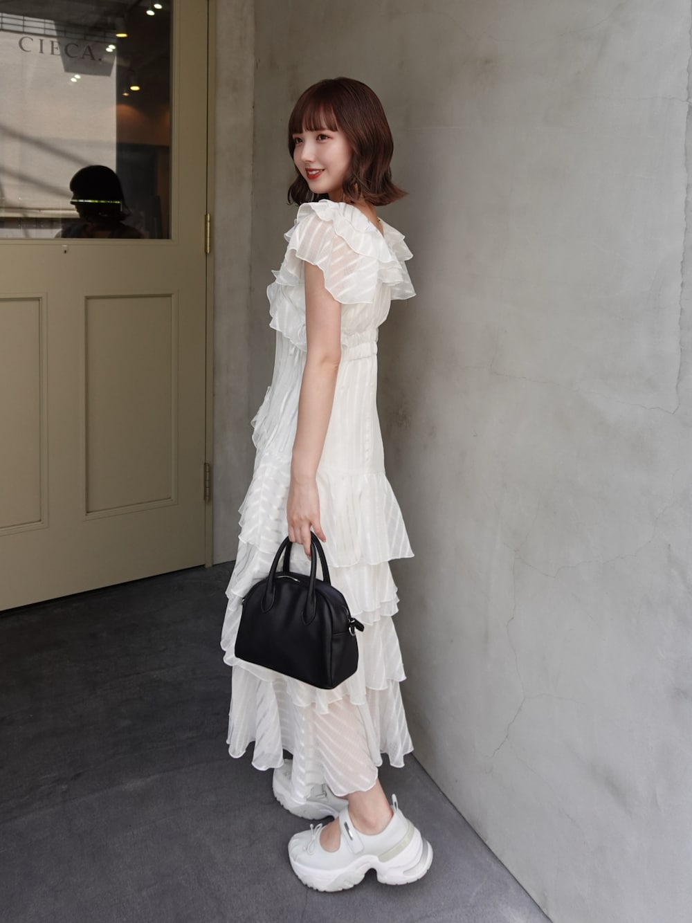 ホワイト系のワンピース、ブラック系のボストンバッグ、ホワイト系のキャミソールを着用したレディースの春コーディネートの1枚目の写真