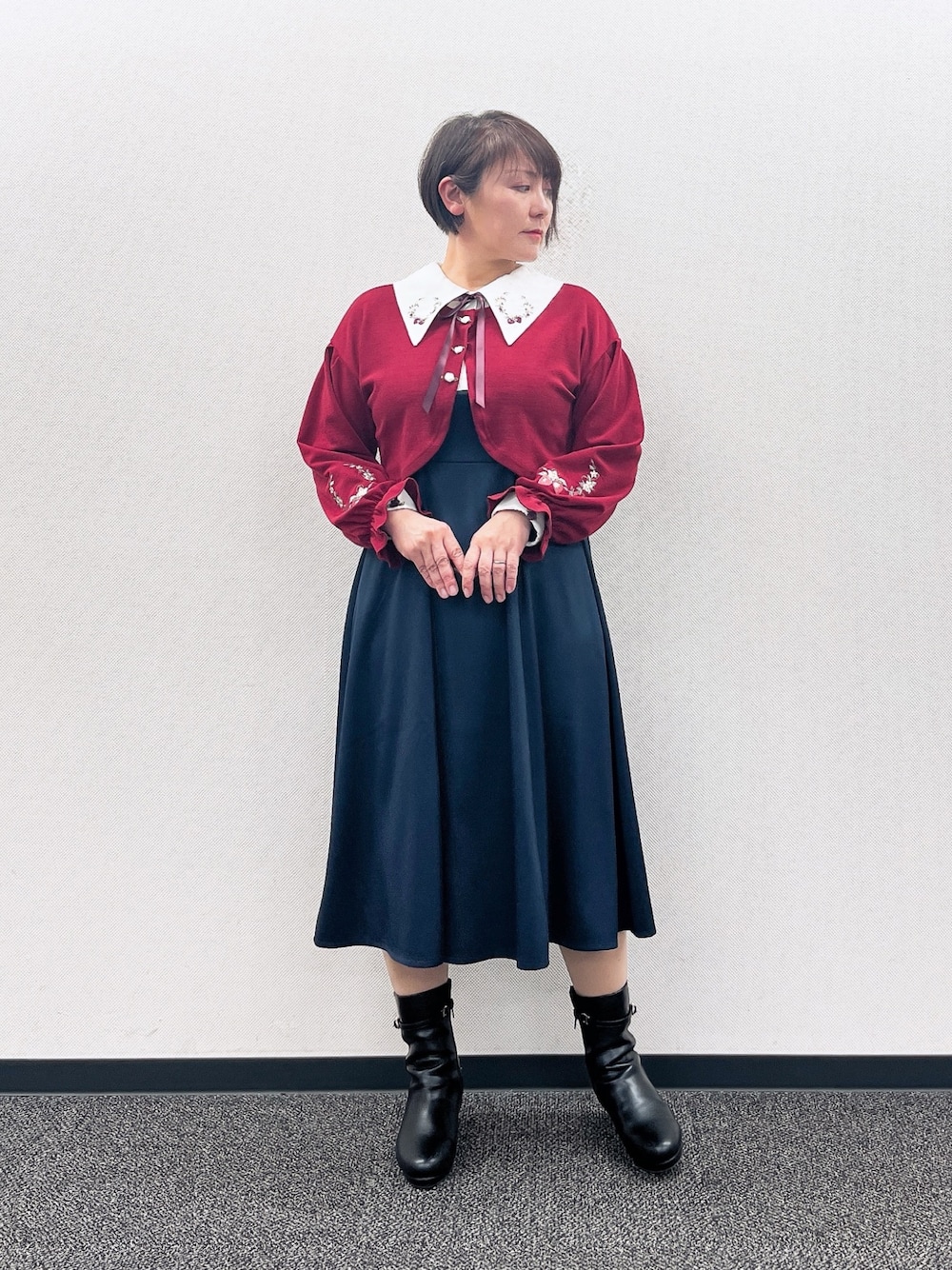 ブルー系のワンピース、レッド系のカーディガン/ボレロ、ブラック系のブーツを着用したレディースの冬コーディネートの1枚目の写真
