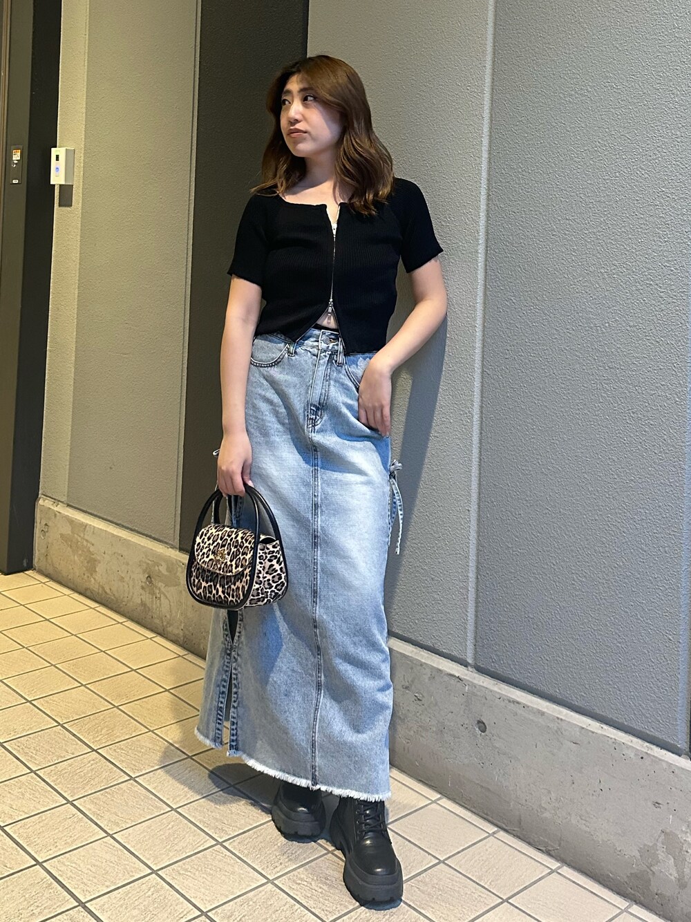 ブルー系のデニムスカート、その他のハンドバッグ、ブラック系のブーツを着用したレディースの春コーディネートの1枚目の写真