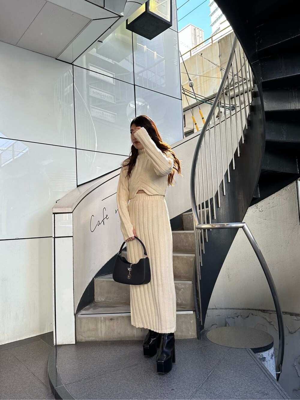 ホワイト系のスカート、ホワイト系のニット/セーター、ブラック系のハンドバッグを着用したレディースの秋コーディネートの1枚目の写真