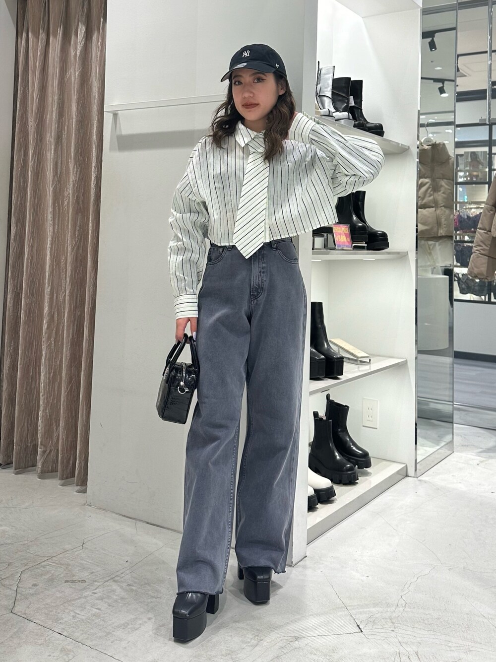 グレー系のデニムパンツ、ホワイト系のシャツ/ブラウス、ブラック系のショルダーバッグを着用したレディースの冬コーディネートの1枚目の写真