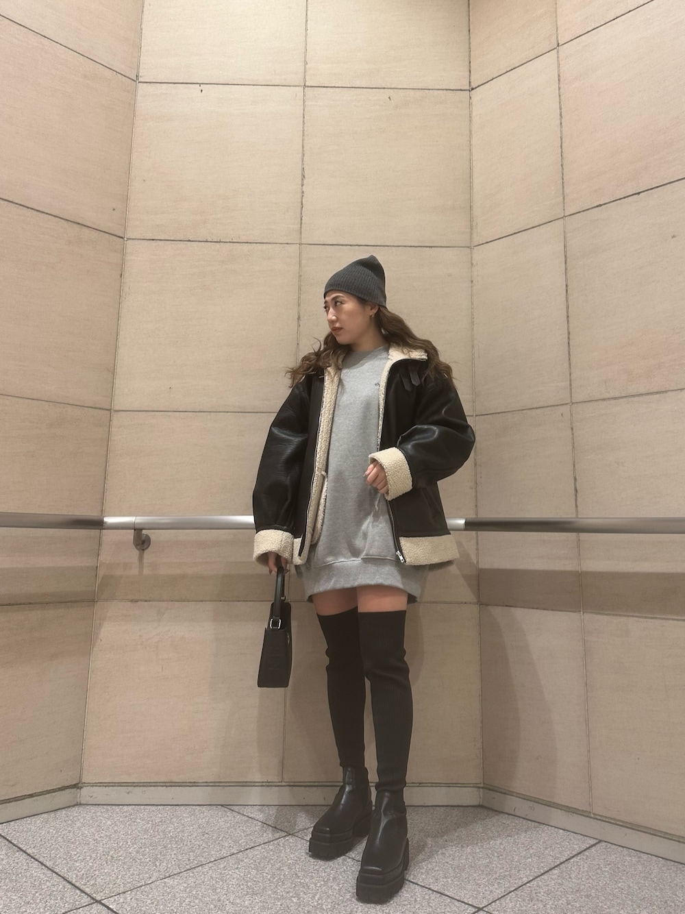 グレー系のスウェット、ブラック系のブルゾン、ブラック系のハンドバッグを着用したレディースの冬コーディネートの1枚目の写真