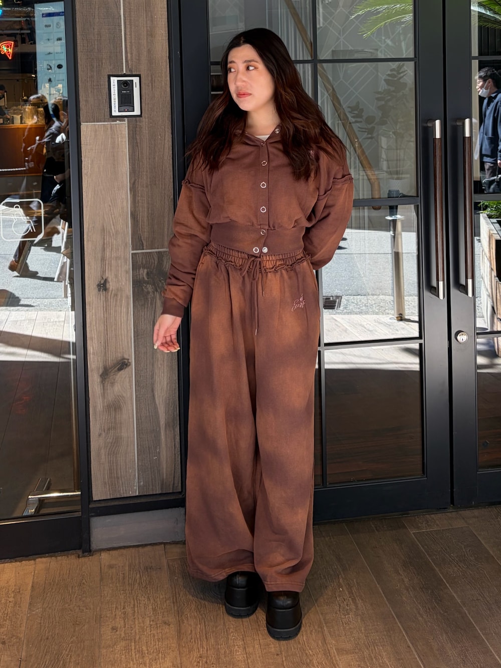 ブラウン系のスウェットパンツ、ブラウン系のパーカー、ブラック系のブーツを着用したレディースの春コーディネートの1枚目の写真