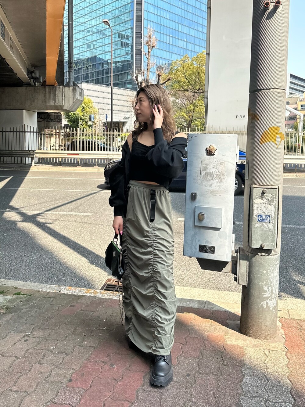 ベージュ系のスカート、ブラック系のカーディガン/ボレロ、ブラック系のショルダーバッグを着用したレディースの春コーディネートの1枚目の写真