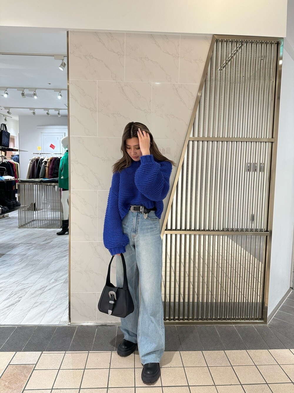 ブラック系のハンドバッグ、ブルー系のニット/セーター、ブルー系のデニムパンツを着用したレディースの冬コーディネートの1枚目の写真